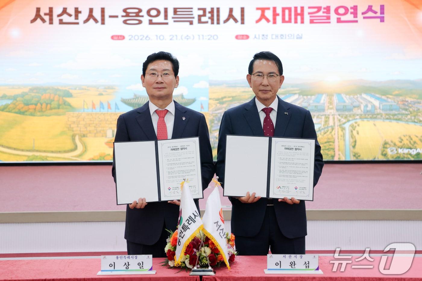 본문 이미지 - 이상일 용인시장(왼쪽)과 이완섭 서산시장이 자매결연 협약서에 서명한 뒤 기념 촬영을 하고 있는 모습.(용인시 제공)