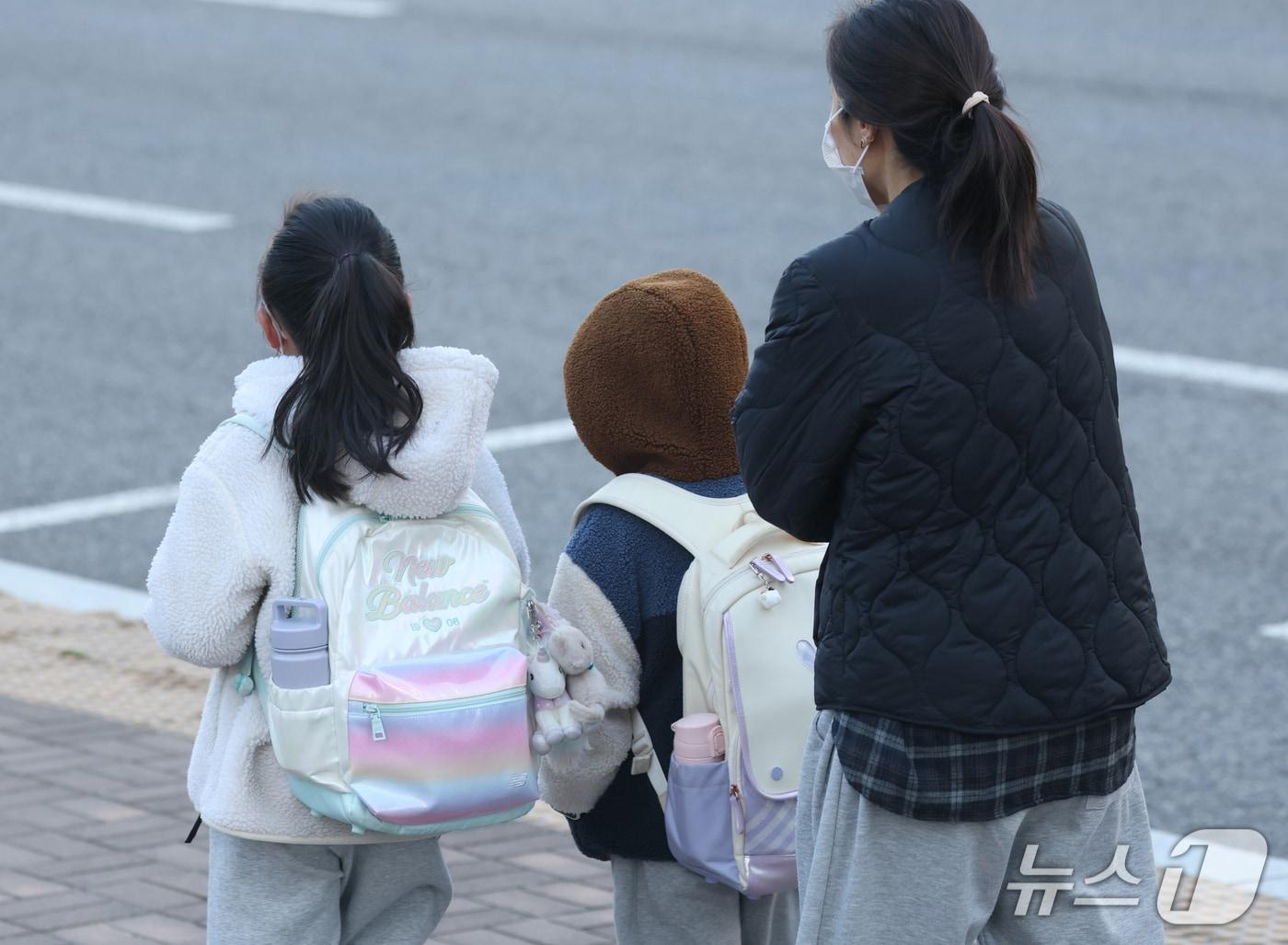 본문 이미지 - 한 초등학교 앞에서 학생들이 두터운 외투를 입고 등교를 하고 있다.(자료사진)