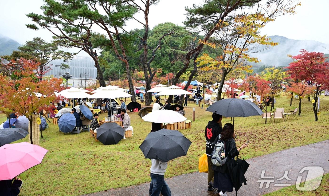 본문 이미지 - 김천 김밥 축제 이튿날인 25일 하루 종일 비가 내린 가운데 축제장을 찾은 방문객들이 가을이 깊어가는 행사장에서 우산을 쓰고 김밥을 먹고 있다. (김천시 제공. 재판매 및 DB 금지) 2026.10.24 ⓒ 뉴스1 정우용 기자