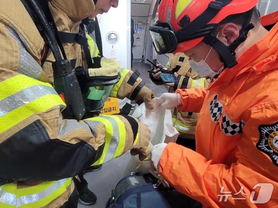 본문 이미지 - 25일 오전 제주국제공항에 도착한 항공기에서 화재가 발생한 보조배터리를 안전조치한 모습.(제주도소방안전본부 제공. 재판매 및 DB 금지)