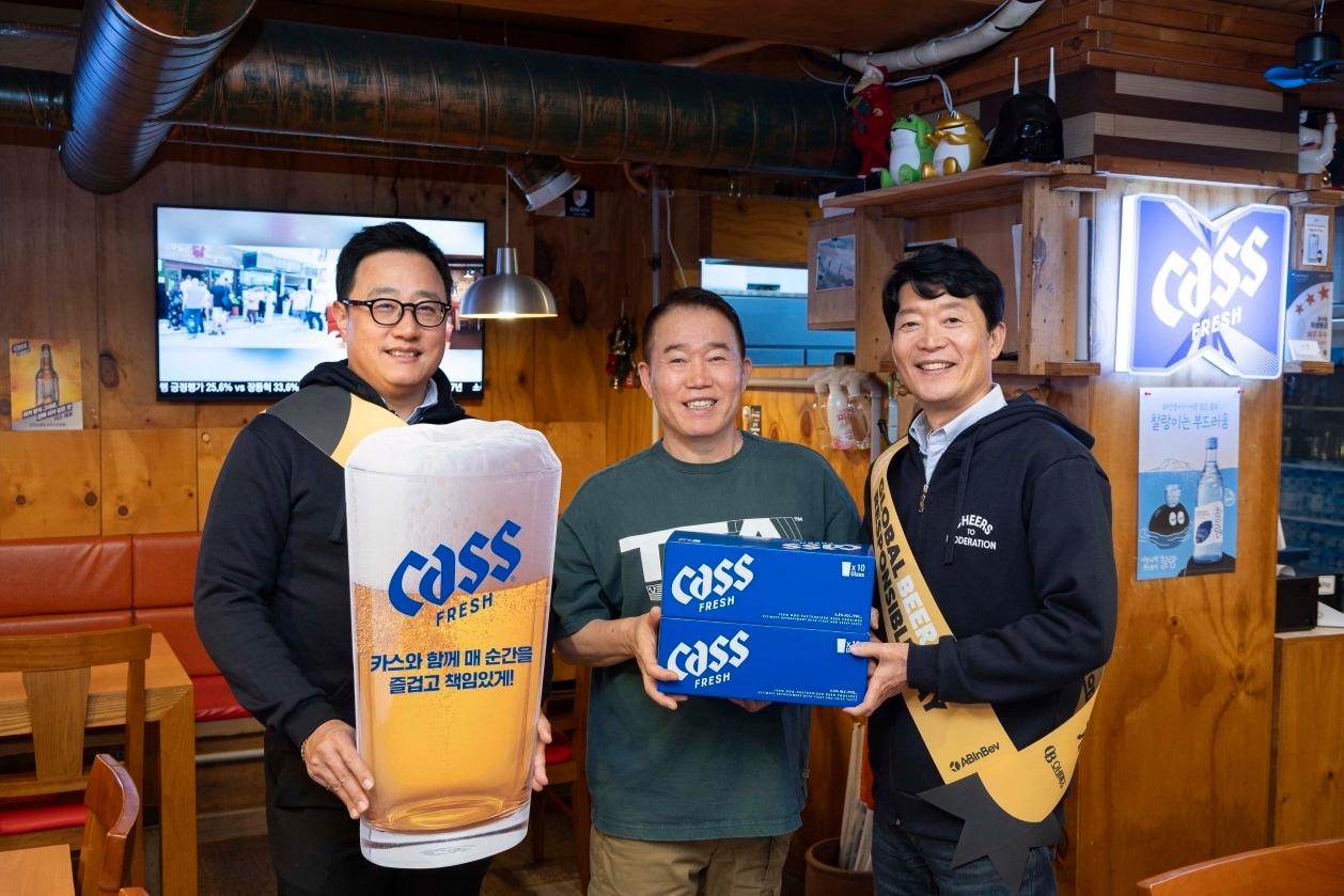 본문 이미지 - 구자범 오비맥주 수석 부사장(왼쪽)과 오비맥주 김병훈 영업 부사장(오른쪽)이 점주에게 책임음주 문구가 담긴 맥주잔을 전달하고 기념사진을 찍고 있다.(오비맥주 제공)