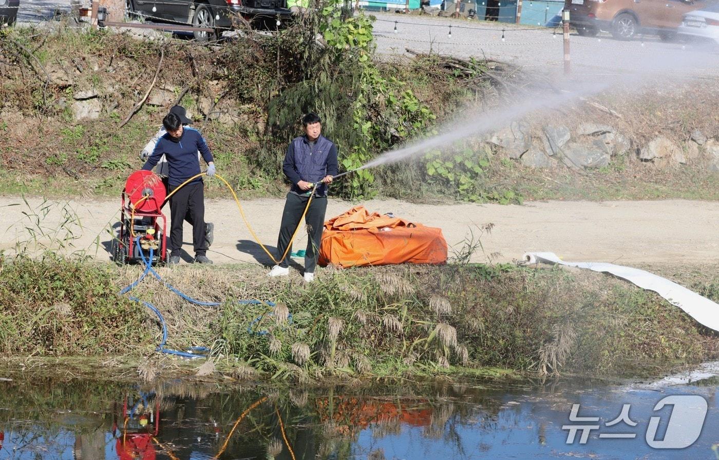 본문 이미지 - 28일 경기 남양주시 월산천 일대에서 진행된 '수질오염사고 대비 합동방제훈련'에서 참석자가 2차 저지선 내부에서 고압 동력 분무기를 이용해 방제작업을 하고 있는 모습.(한강청 제공)