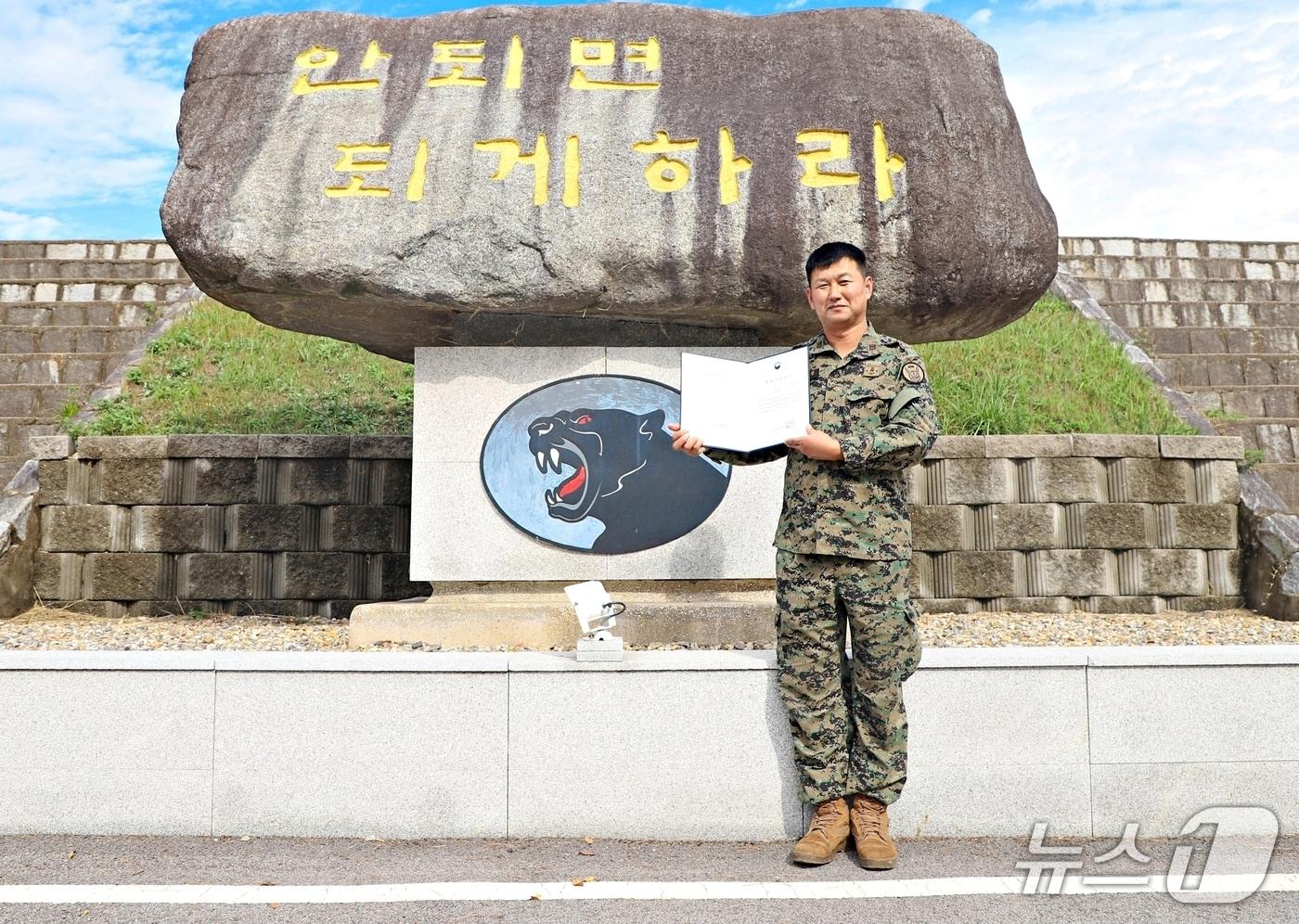 본문 이미지 - 혈액질환 환자에게 조혈모세포를 기증한 육군특수전사령부 흑표부대 김정 원사가 부대 표지석 앞에서 기증서를 들어 보이고 있다.(흑표부대 제공. 재판매 및 DB 금지) 2026.10.29/뉴스1