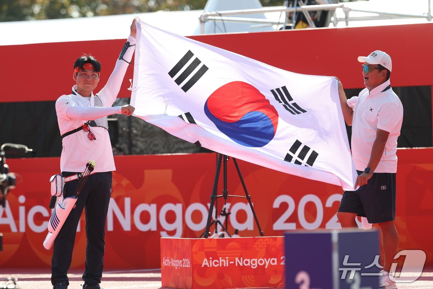 본문 이미지 - 대한민국 이우석이 3일 일본 오카자키 중앙종합공원 다목적광장에서 열린 2026 아이치·나고야 아시안게임 양궁 리커브 남자 개인전 결승에서 일본 나카니시 준야를 꺾고 금메달을 확정지은 후 태극기를 펼쳐보이고 있다. 2026.10.3 ⓒ 뉴스1 김도우 기자