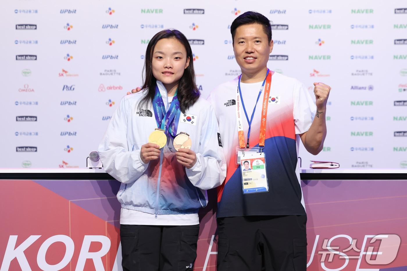 본문 이미지 - 대한민국 서채현과 박희용 감독이 4일 일본 라이브스 나고야 코리아하우스에서 열린 2026 아이치·나고야 아시안게임 금메달리스트 기자회견에서 금메달과 동메달을 들어 보이고 있다. 서채현은 스포츠 클라이밍 여자 리드 금메달과 볼더 동메달을 획득했다. 2026.10.4 ⓒ 뉴스1 안은나 기자