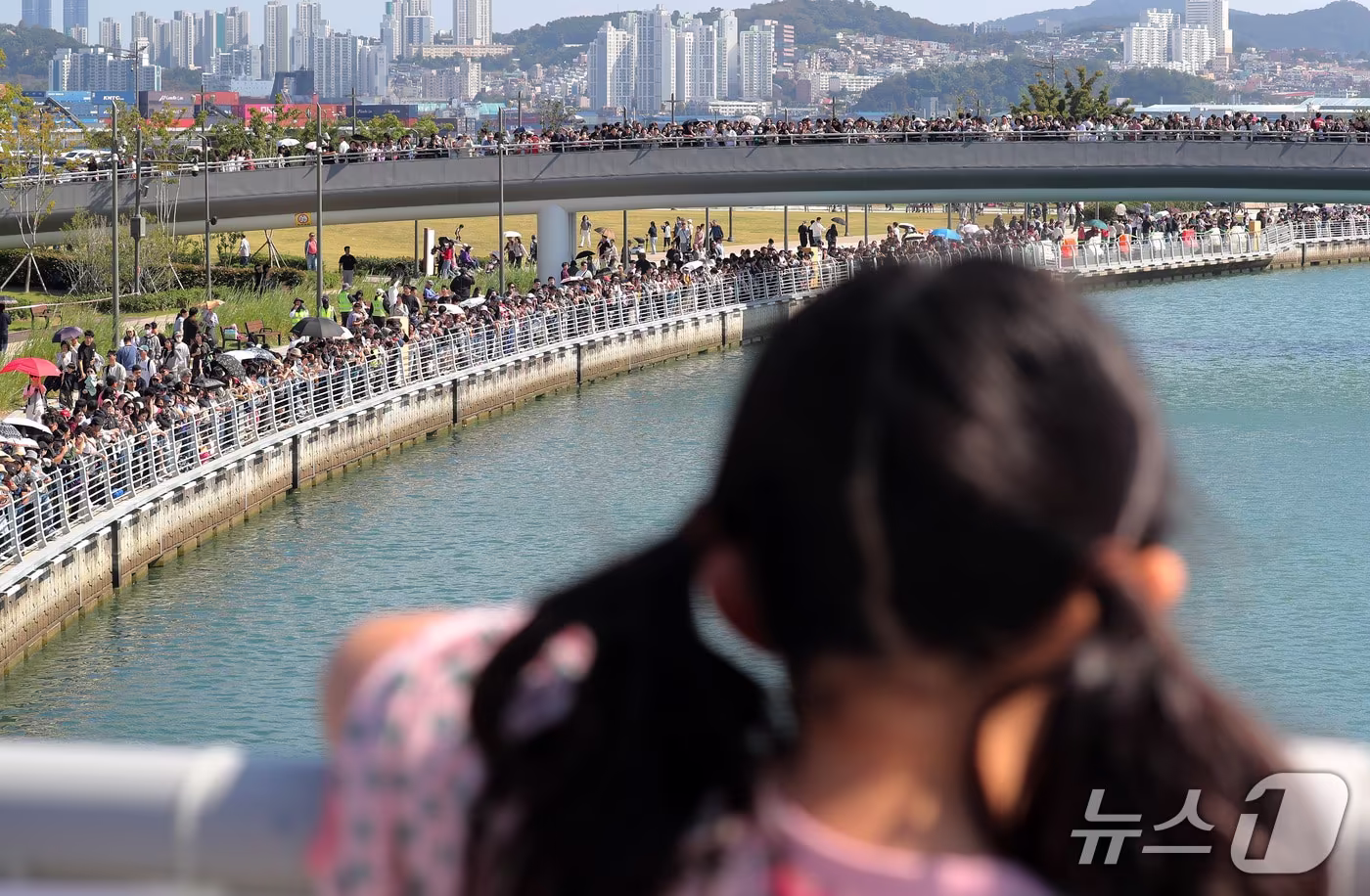 본문 이미지 - 개천절 연휴 마지막 날인 5일 부산 동구 북항 친수공원 인공수로에서 한 어린이가 상어 '부캉이'를 기다리고 있다. 2026.10.5 ⓒ 뉴스1 윤일지 기자