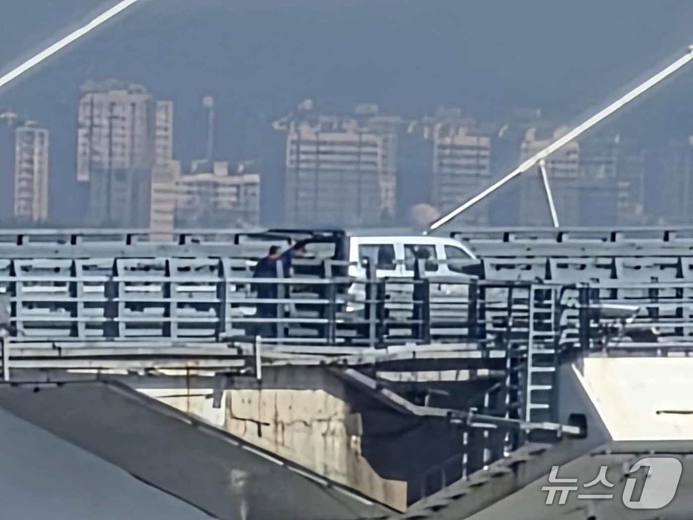 본문 이미지 - 6일 오전 중국 랴오닝성 단둥에서 바라본 신압록강대교 위에 뒷문이 열린 승합차가 멈춰 서 있고 인부들이 차량 뒤편에 서 있다. 이들의 작업 목적과 대교 개통식 관련성은 확인되지 않았다. 2026.10.6 ⓒ 뉴스1 노민호 특파원