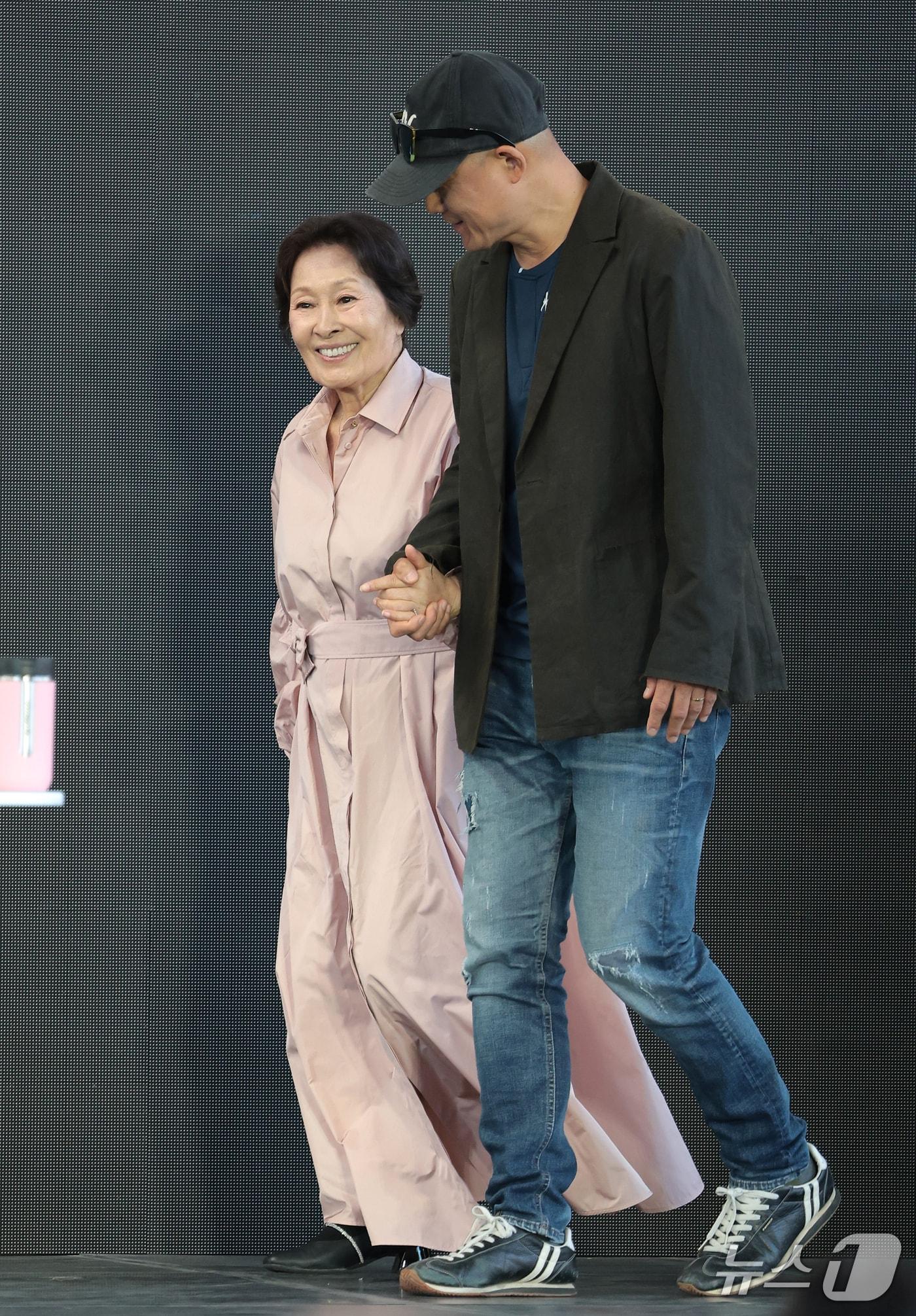 본문 이미지 - 배우 김혜자가 8일 부산 해운대구 영화의전당 루프씨어터에서 열린 ‘제31회 부산국제영화제’ 영화 ‘여전히 찬란하게’ 야외무대인사에서 송일곤 감독(오른쪽) 손을 잡고 입장하고 있다. 2026.10.8 ⓒ 뉴스1 권현진 기자