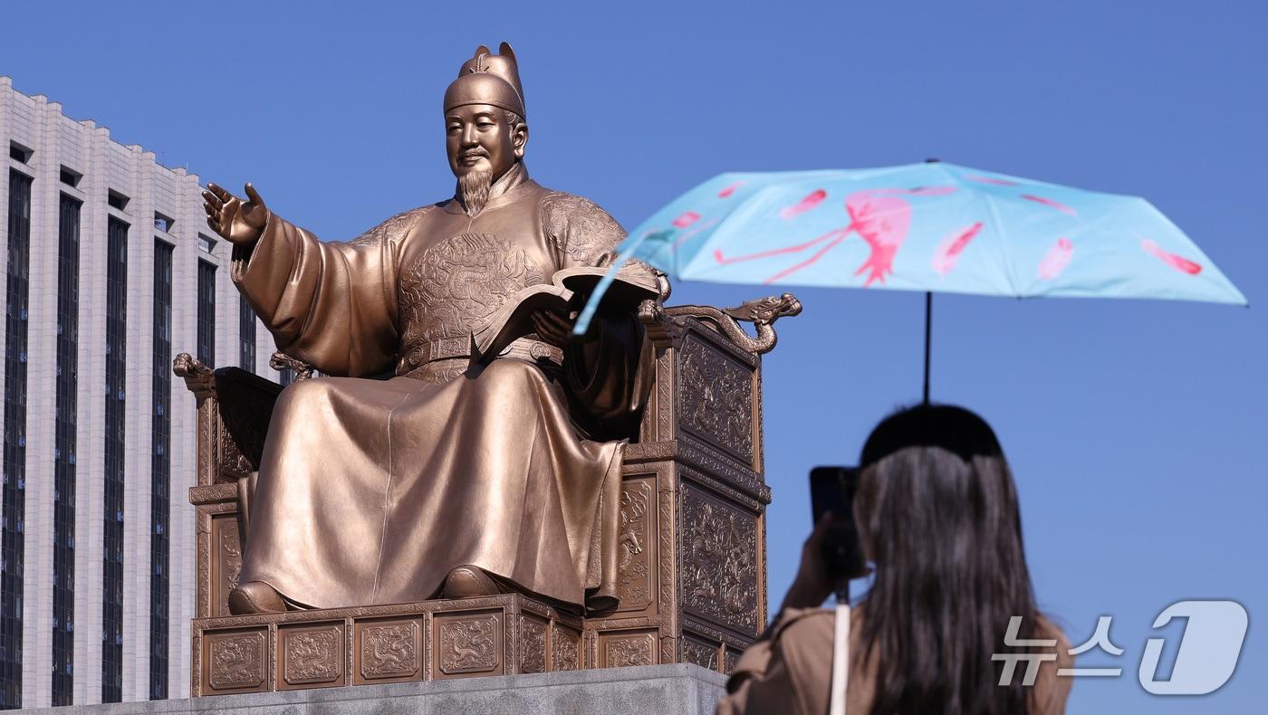 본문 이미지 - 한글날 제정 100주년을 하루 앞둔 8일 서울 종로구 광과문광장에서 한 시민이 세종대왕 동상을 스마트폰에 담고 있다. 올해는 세종대왕의 한글 창제 580돌이며, 한글날 제정 100주년이다. 2026.10.8 ⓒ 뉴스1 박지혜 기자
