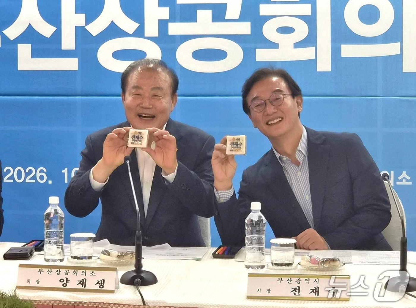 본문 이미지 - 8일 부산상공회의소를 방문한 전재수 부산시장(오른쪽)이 양재생 부산상공회의소 회장과 함께 자신의 이름이 새겨진 축하 떡을 들어 보이며 환하게 웃고 있다. 2026.10.8뉴스1 ⓒ News1 임순택 기자