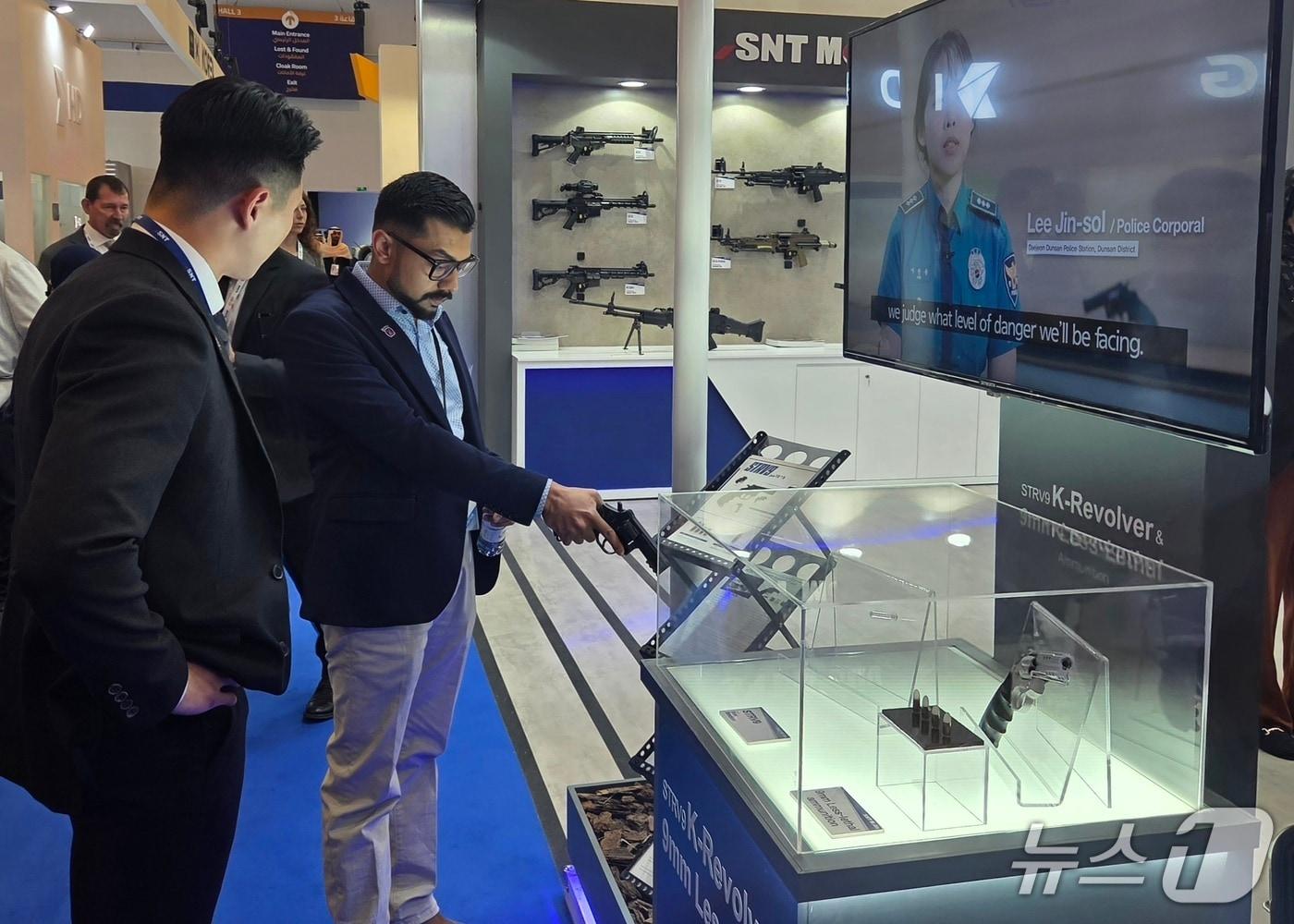 본문 이미지 - WDS 2026 내 SNT모티브 전시관을 찾은 한 관계자가 저위험권총을 살펴보고 있는 모습 (SNT모티브 제공. 재판매 및 DB금지)