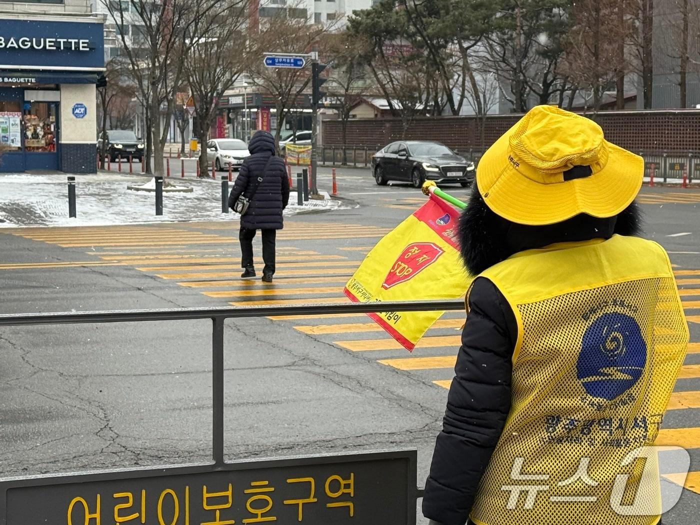 본문 이미지 - 아침 최저기온이 -2도를 기록한 10일 오전 9시 광주 서구 치평동의 한 아파트 단지에서 노인 일자리 참여자 A 씨가 교통 안내를 하고 있다. 2026.2.10 ⓒ 뉴스1 이수민 기자