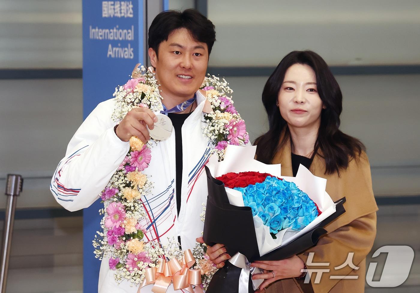 본문 이미지 - 2026 밀라노·코르티나담페초 동계 올림픽에서 한국에 400번째 올림픽 메달을 안겨준 스노보드 김상겸이 10일 오전 인천국제공항을 통해 귀국하며 은메달을 들어보이고 있다. 오른쪽은 아내 박한솔 씨. 2026.2.10 ⓒ 뉴스1 김민지 기자