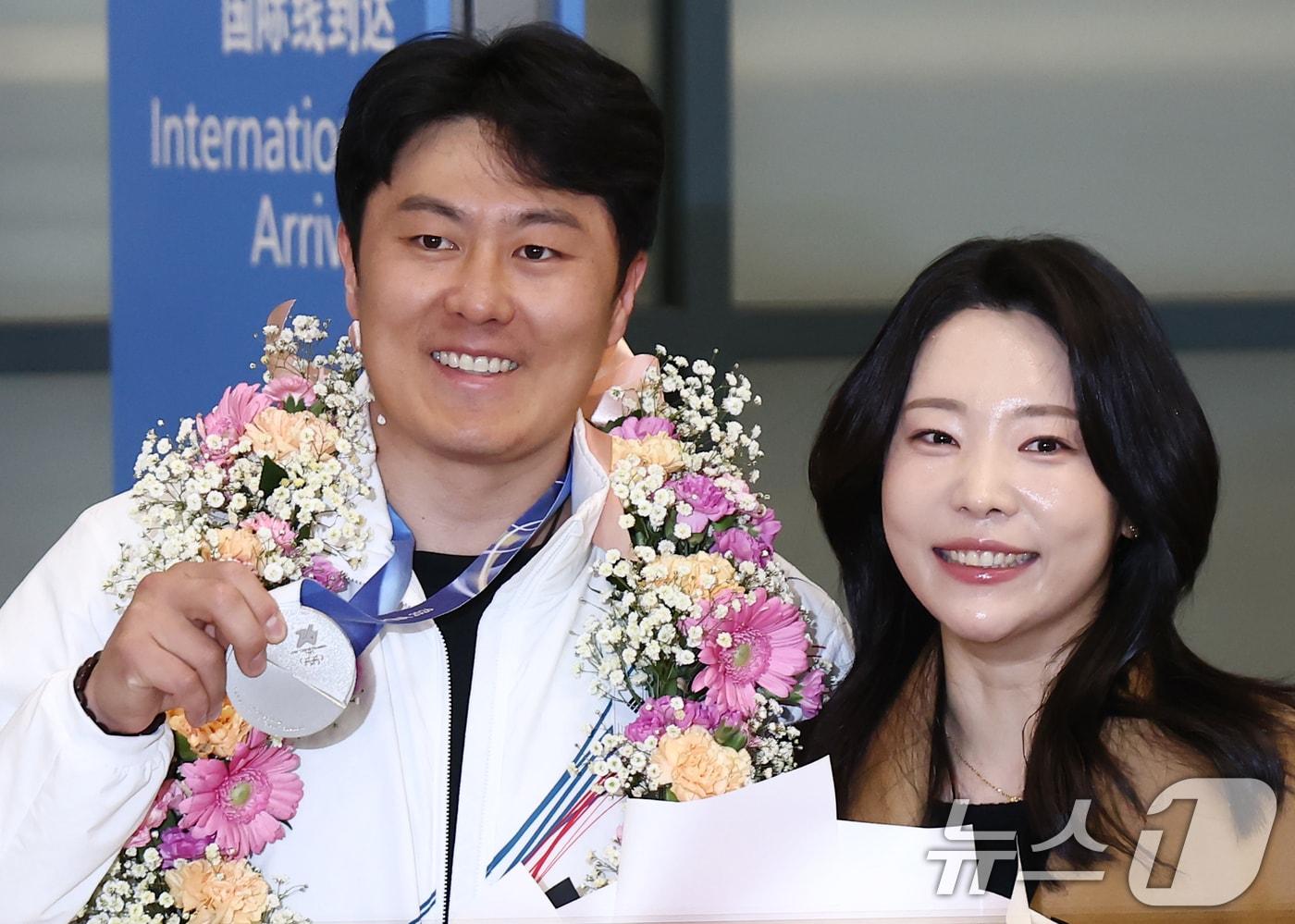 본문 이미지 - 2026 밀라노·코르티나담페초 동계 올림픽에서 한국에 400번째 올림픽 메달을 안겨준 스노보드 김상겸이 10일 오전 인천국제공항을 통해 귀국하며 은메달을 들어보이고 있다. 오른쪽은 아내 박한솔 씨. 2026.2.10 ⓒ 뉴스1 김민지 기자