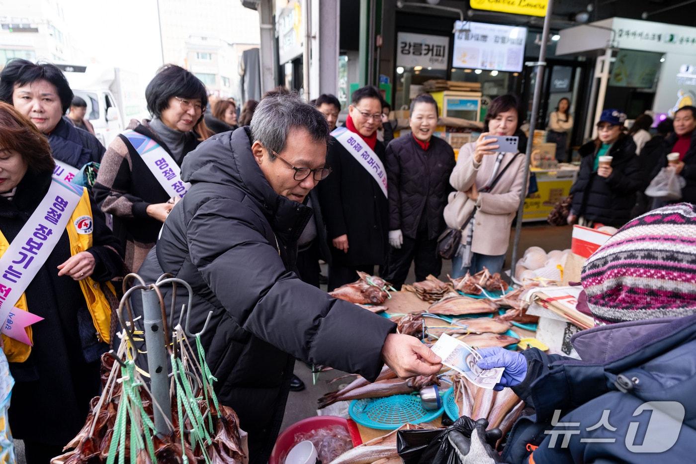 본문 이미지 - 김홍규 강원 강릉시장이 11일 강릉 중앙·성남시장에서 열린 전통시장 장보기 행사에서 지역 화폐를 내고 물건을 구입하고 있다.(강릉시 제공, 재판매 및 DB 금지) 2026.2.11/뉴스1