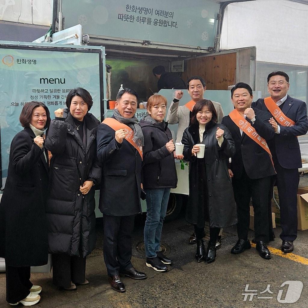 본문 이미지 - 한화생명이 추운 날씨에도 영업현장에서 힘쓰는 FP들에게 감사의 마음을 전하기 위해 ‘H카페’를 운영한다. 지난달 2일(금) 운영을 시작한 이번 행사는 이달 27일(금)까지 한화생명금융서비스와 GA, 한화라이프랩, 피플라이프 등 전국 97개 지역단과 사업단을 찾아간다. 11일(수) 한화생명금융서비스 홍승표 평택지역단장(오른쪽 첫번째)과 지점장, FP들이 음료와 간식을 나누고 기념촬영을 하고 있다./사진제공=한화생명