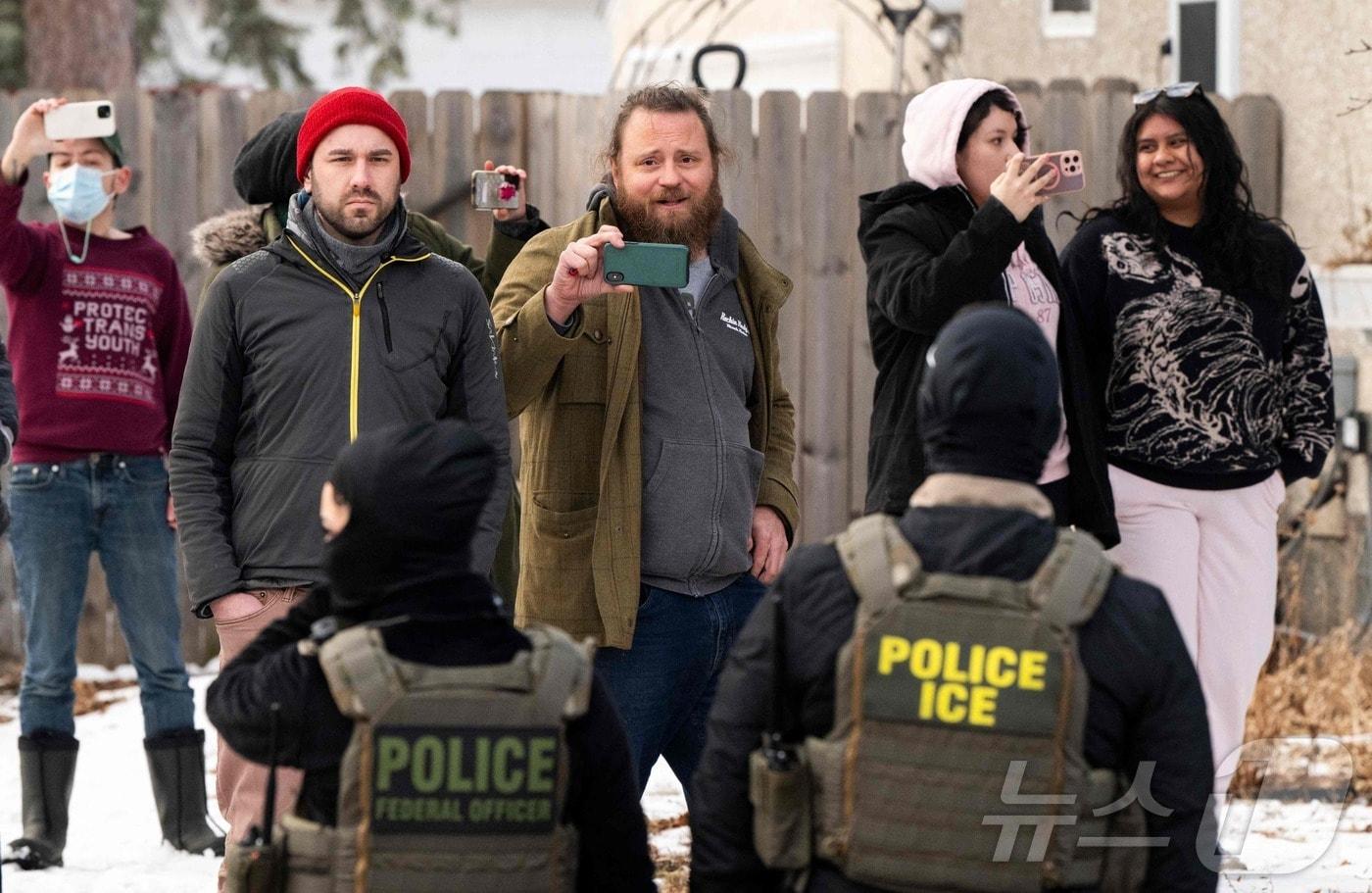 본문 이미지 - 5일(현지시간) 미네소타 미니애폴리스에서 시민들이 이민세관단속국(ICE) 요원들을 경계하며 이들의 모습을 촬영하고 있다. 2026.02.05. ⓒ AFP=뉴스1