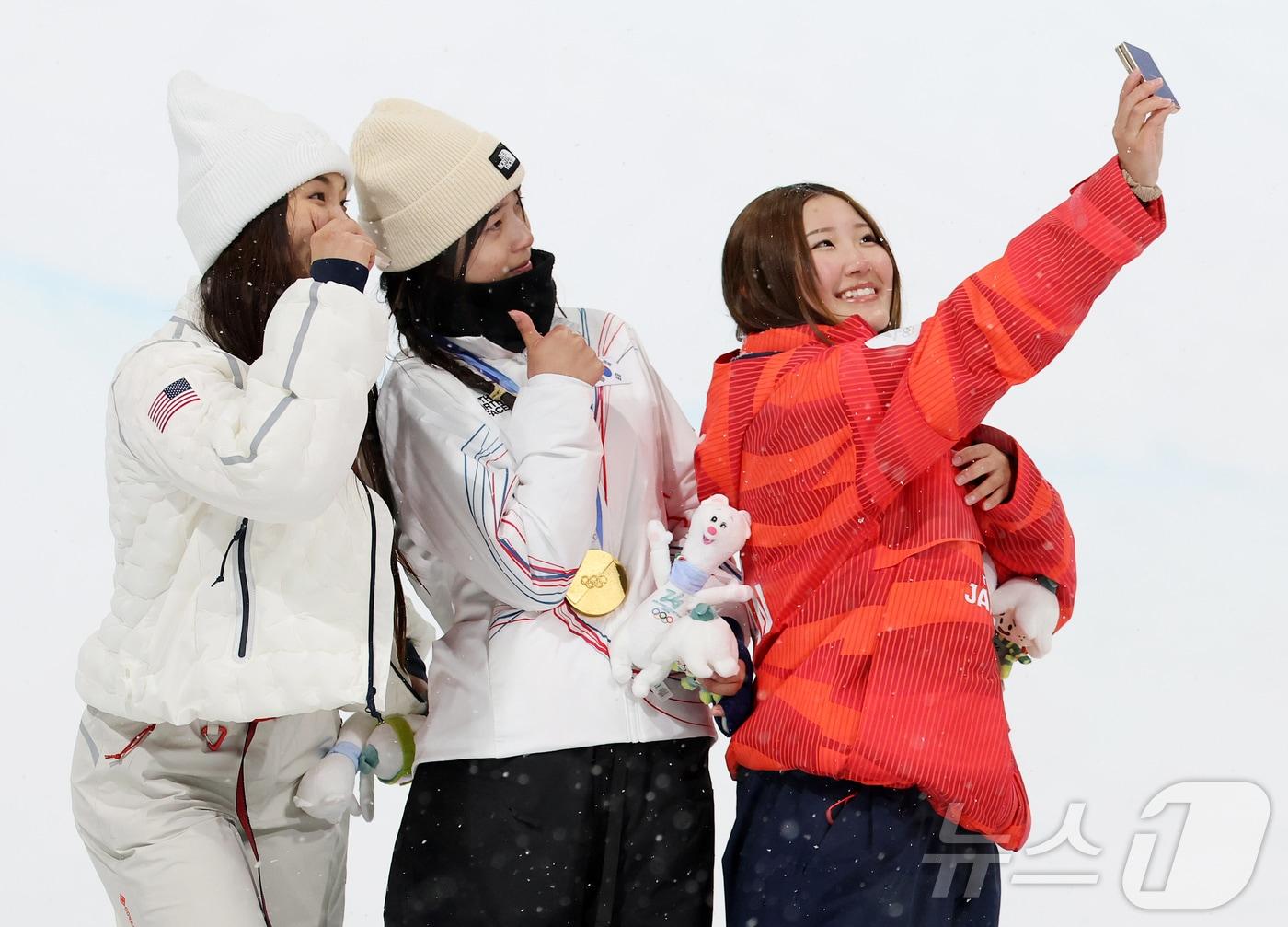 본문 이미지 - 12일(현지시간) 이탈리아 리비뇨 스노파크에서 열린 2026 밀라노·코르티나담페초 동계올림픽 스노보드 여자 하프파이프 결선에서 90.25점을 받아 금메달을 획득한 스노보드 최가온이 은메달리스트 미국의 클로이 킴, 동메달리스트 일본의 요노 미쓰키와 셀피를 찍고 있다. 2026.2.13 ⓒ 뉴스1 김진환 기자