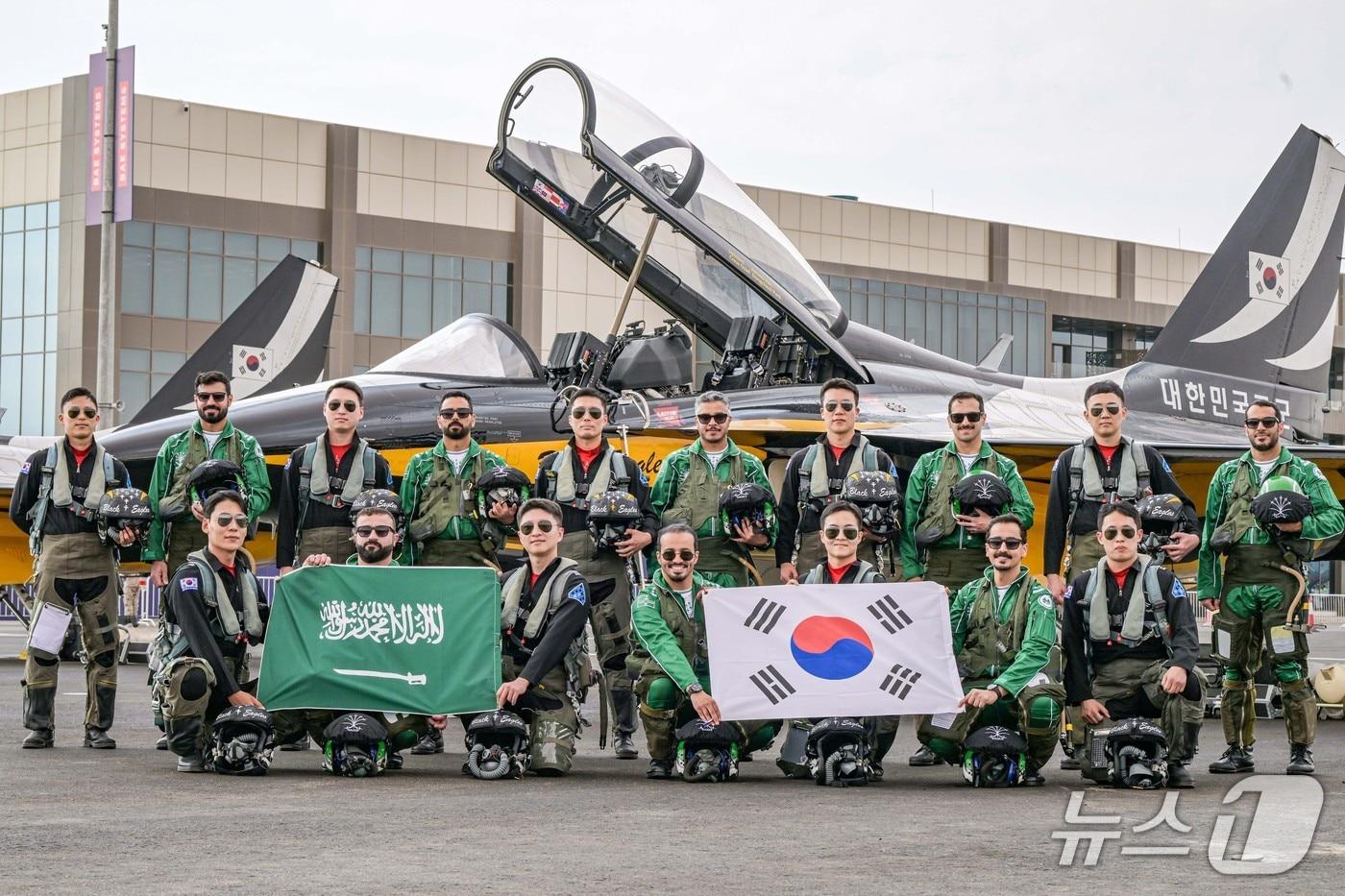 본문 이미지 - 대한민국 공군 특수비행팀 블랙이글스가 지난 8일부터 12일(현지시간)까지 사우디아라비아에서 열리는 ‘세계방위산업전시회'(WDS 2026)에 참가해 에어쇼를 선보였다. 사진은 지난 2월 7일(토) 진행된 '블랙이글스-사우디 호크스(Saudi Hawks) 지상교류 행사'에서 블랙이글스 조종사들과 사우디 호크스 조종사들이 T-50B 항공기 앞에서 양국 국기를 들고 함께 기념촬영을 하고 있는 모습. 2026.2.13./ⓒ 뉴스1(공군 제공)