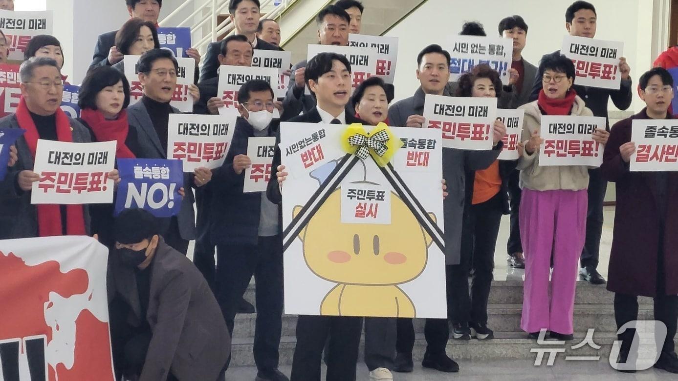 본문 이미지 - 대전충남 졸속 통합 반대 범시민 기자회견이 13일 오후 대전시의회 1층 로비에서 열렸다. 참석자들은 꿈돌이 근조 리본 퍼포먼스를 펼쳤다 (박종명 기자) / 뉴스1