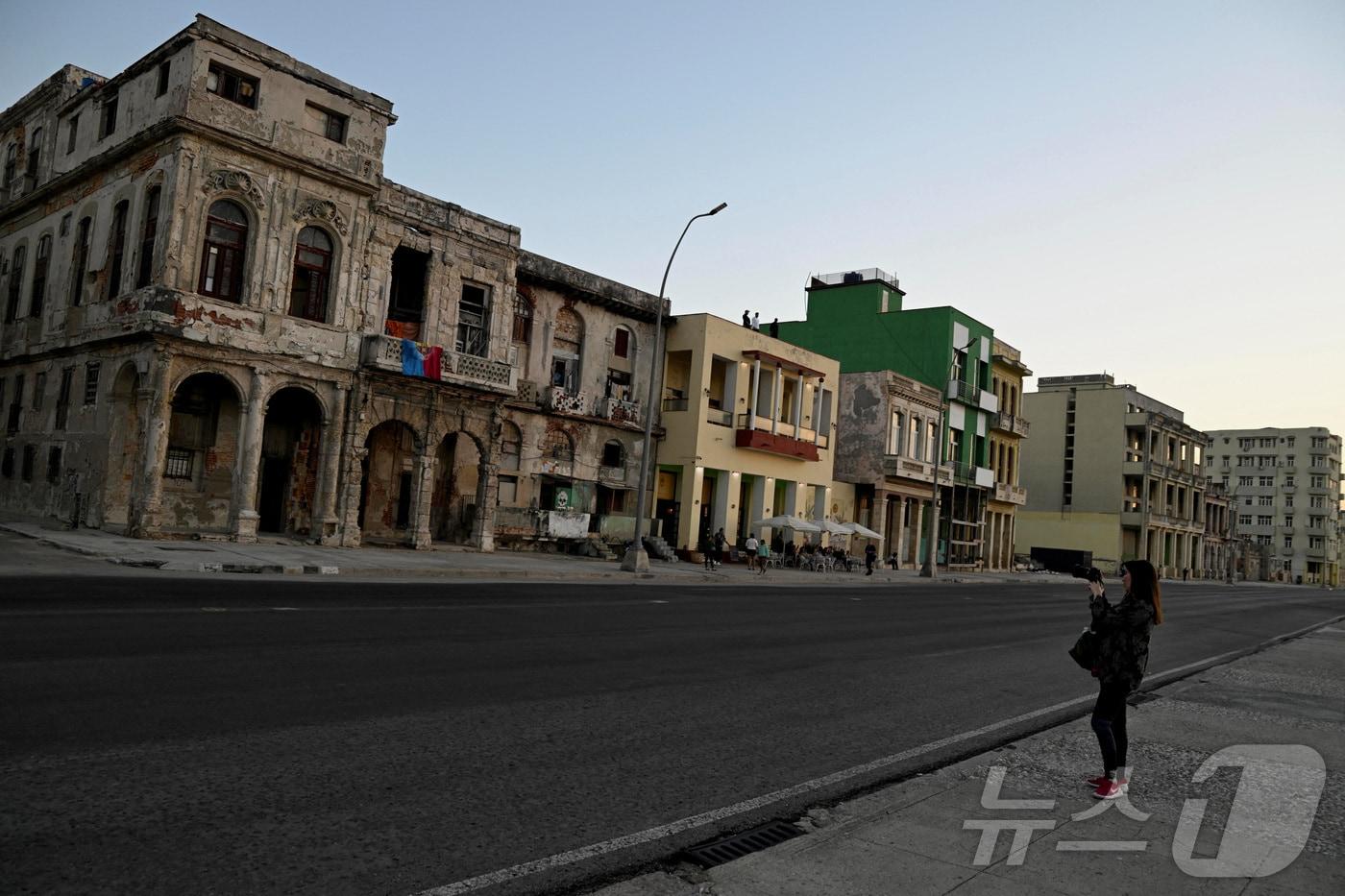 본문 이미지 - 지난 11일(현지시간) 미국이 쿠바의 석유 수송을 차단한 가운데 한 관광객이 쿠바 아바나의 말레콘 해변가에서 사진을 찍고 있다. 2026.02.11. ⓒ 로이터=뉴스1
