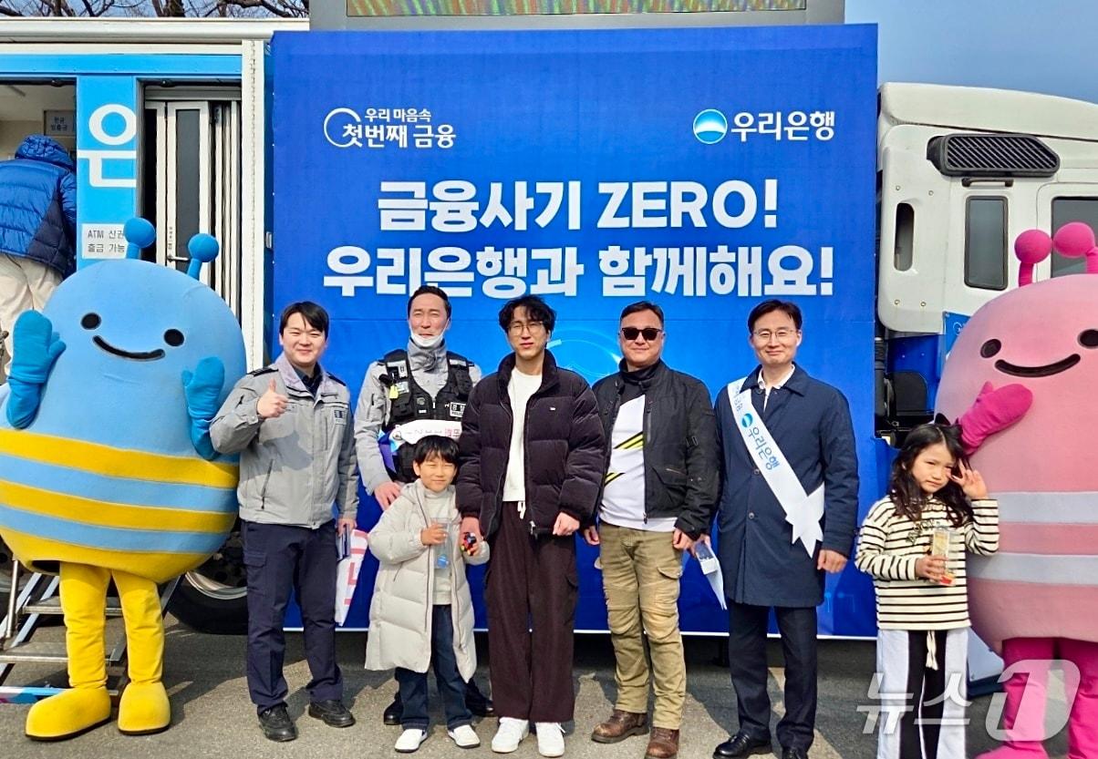 본문 이미지 - 13일 경부고속도로 하행선 망향휴게소에서 우리은행 정철경 채널전략부장(오른쪽 두 번째), 천안서북경찰서 경찰관이 귀성객과 기념사진을 촬영하고 있다. 2026.02.13 / 사진제공=우리은행