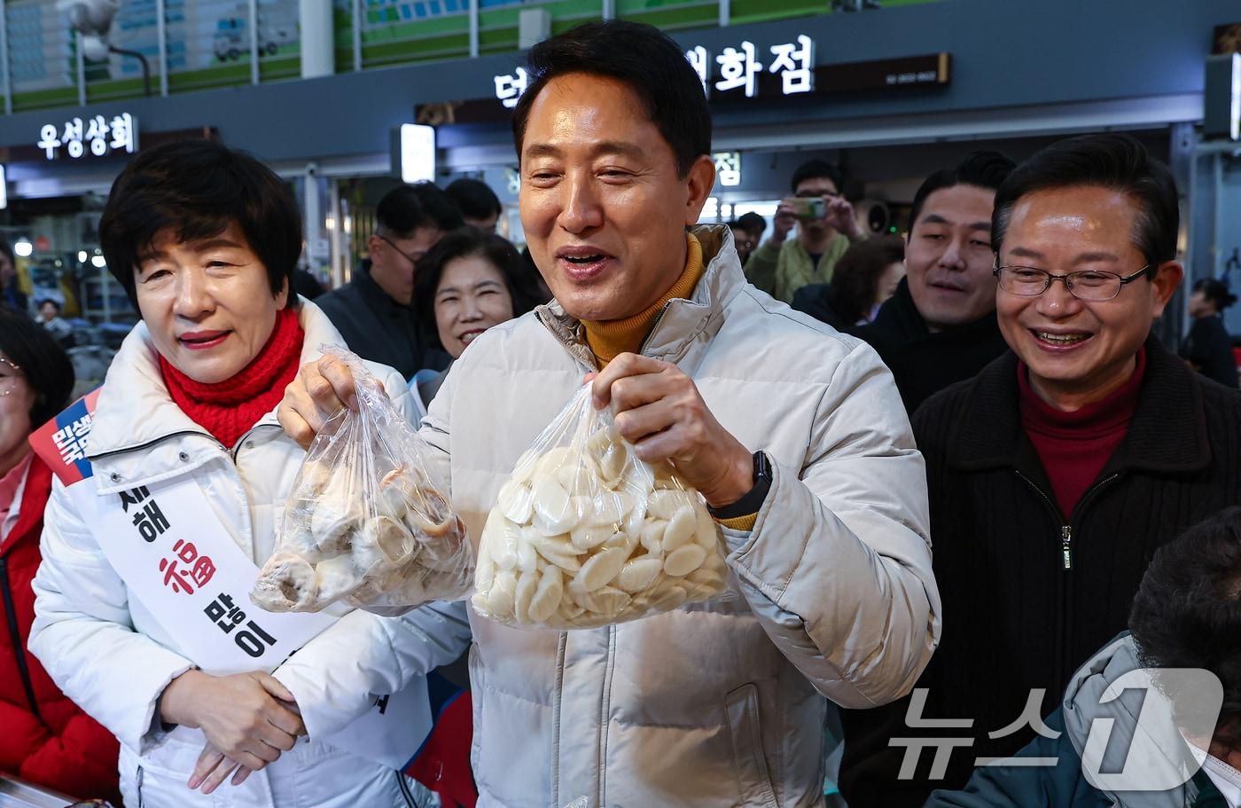 본문 이미지 - 오세훈 서울시장이 설 연휴 첫날인 14일 서울 영등포전통시장을 찾아 떡을 구입하고 있다. 2026.2.14 ⓒ 뉴스1 김도우 기자