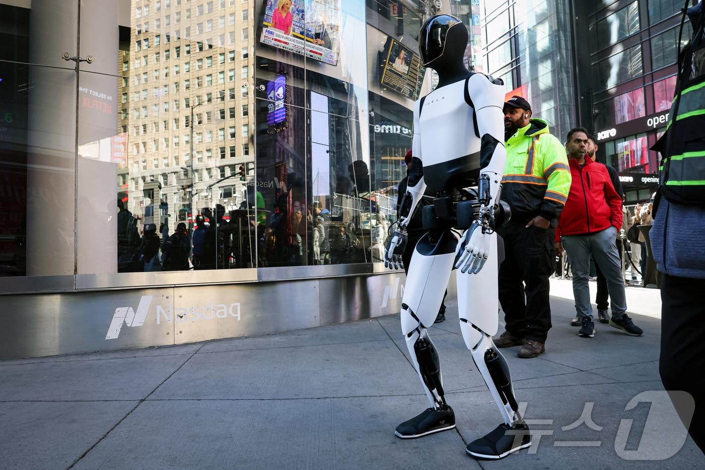본문 이미지 - 미국 뉴욕의 나스닥 증권거래소 앞에서 테슬라가 개발한 휴머노이드 로봇 이 걸어가는 모습(자료사진). 2025.10.27. ⓒ 로이터=뉴스1