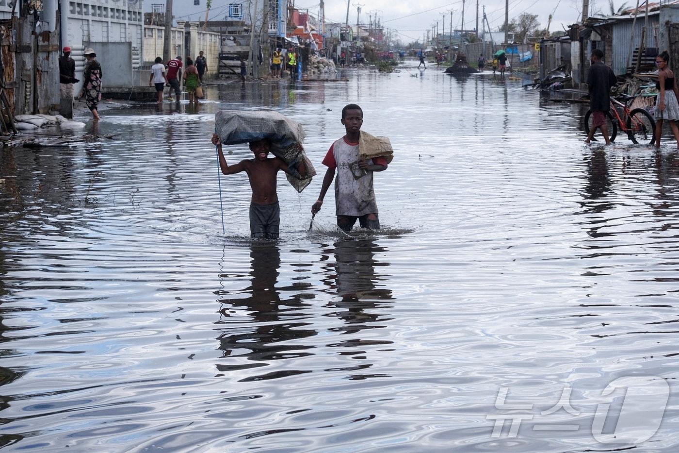 본문 이미지 - 지난 12일 사이클론 '게자니'가 마다가스카르 항구 도시 토아마시나를 휩쓸고 지나간 뒤 아이들이 침수된 거리를 걷고 있다. ⓒ 로이터=뉴스1