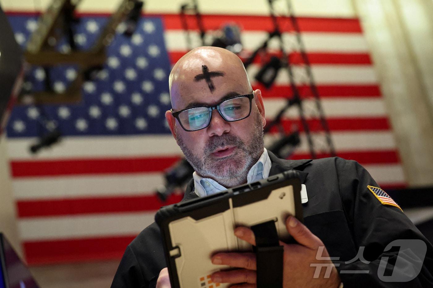 본문 이미지 - 18일(현지시간) '재의 수요일'을 맞아 이마에 십자가 표시를 한 트레이더가 뉴욕증권거래소에서 거래 업무를 하고 있다. 2026.02.18. ⓒ 로이터=뉴스1