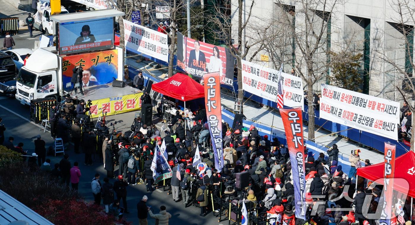 본문 이미지 - 윤석열 전 대통령의 12·3 비상계엄 관련 내란 우두머리 등 혐의 1심 선고 기일인 19일 서울 서초구 중앙지방법원 인근에서 지지자들이 지귀연 판사의 판결문 낭독 중계를 보고 있다. 2026.2.19 ⓒ 뉴스1 안은나 기자