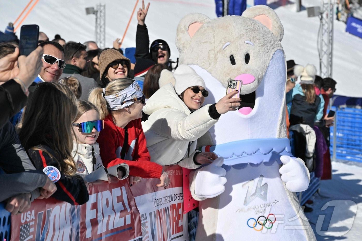 본문 이미지 - 8일(현지시각) 코리티나담페초 알파인 스키 센터에서 열린 2026 밀라노·코르티나담페초 동계올림픽 여자 활강 경기를 앞두고 관중들이 마스코트 티나와 셀카를 찍고 있는 모습.  ⓒ AFP=뉴스1