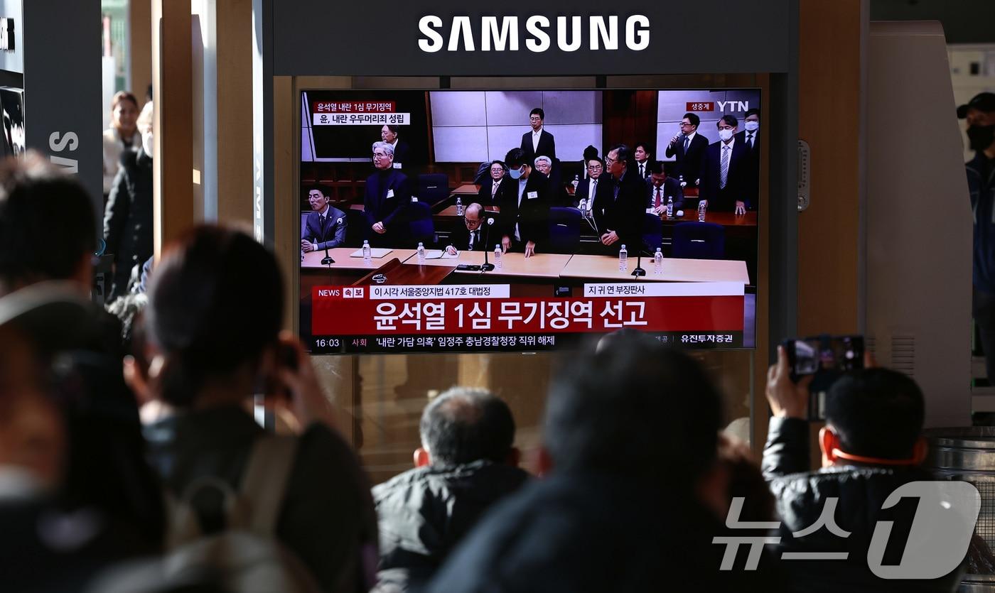 본문 이미지 - 19일 오후 서울역 대합실에 설치된 TV를 통해 윤석열 전 대통령의 내란 우두머리 혐의 1심 선고가 생중계 되고 있다. 윤 전 대통령은 2024년 12월 3일 비상계엄을 선포한 지 443일 만에 무기징역을 선고받았다. 2026.2.19 ⓒ 뉴스1 구윤성 기자