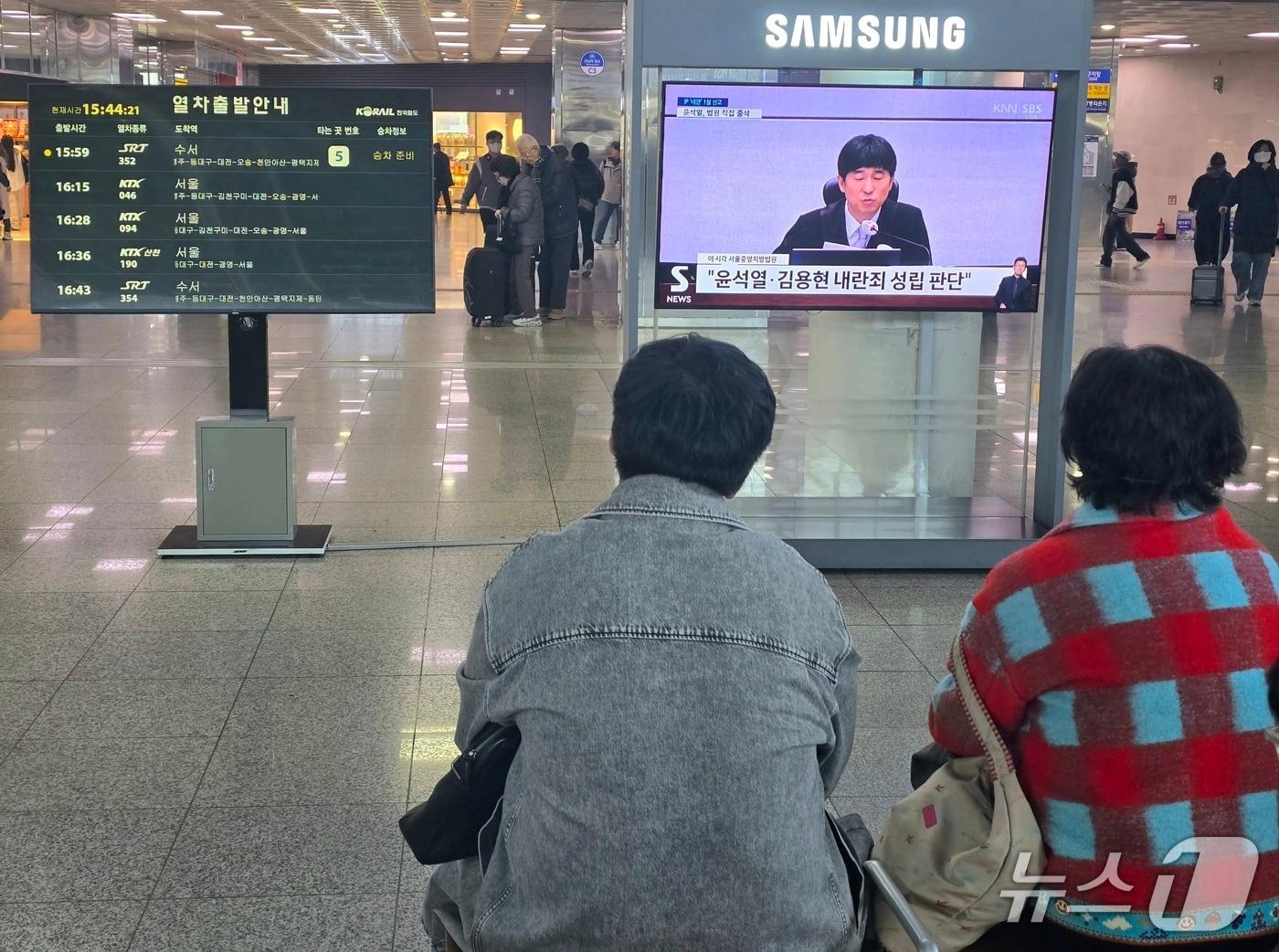 본문 이미지 - 19일 오후 시민들이 부산역 2층에 마련된 TV를 통해 윤석열 전 대통령의 내란 우두머리 혐의 1심 선고를 지켜보고 있다.2026.2.19/뉴스1 ⓒ News1 이주현 기자