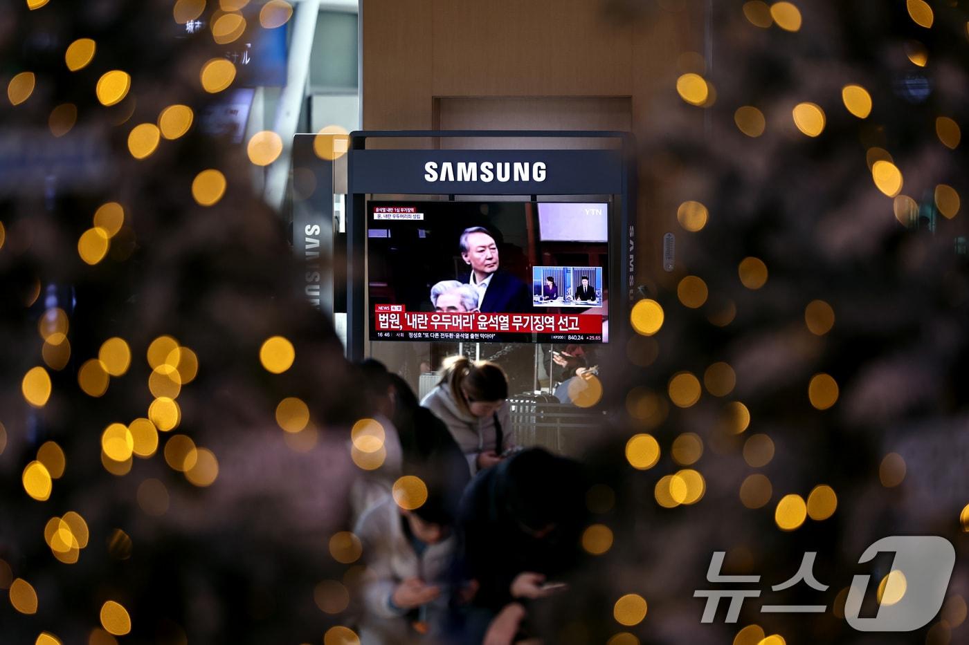 본문 이미지 - 19일 오후 서울역 대합실에 설치된 TV를 통해 윤석열 전 대통령의 내란 우두머리 혐의 1심 선고 관련 뉴스가 나오고 있다. 윤 전 대통령은 2024년 12월 3일 비상계엄을 선포한 지 443일 만에 무기징역을 선고받았다. 2026.2.19 ⓒ 뉴스1 구윤성 기자