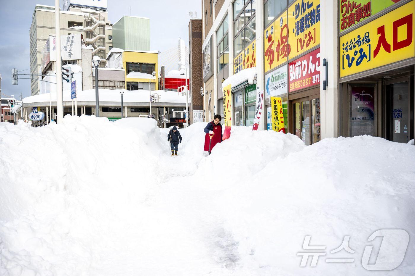본문 이미지 - 30일 일본 아오모리현 아오모리시의 한 가게 앞에서 직원이 눈을 치우고 있다. ⓒ AFP=뉴스1