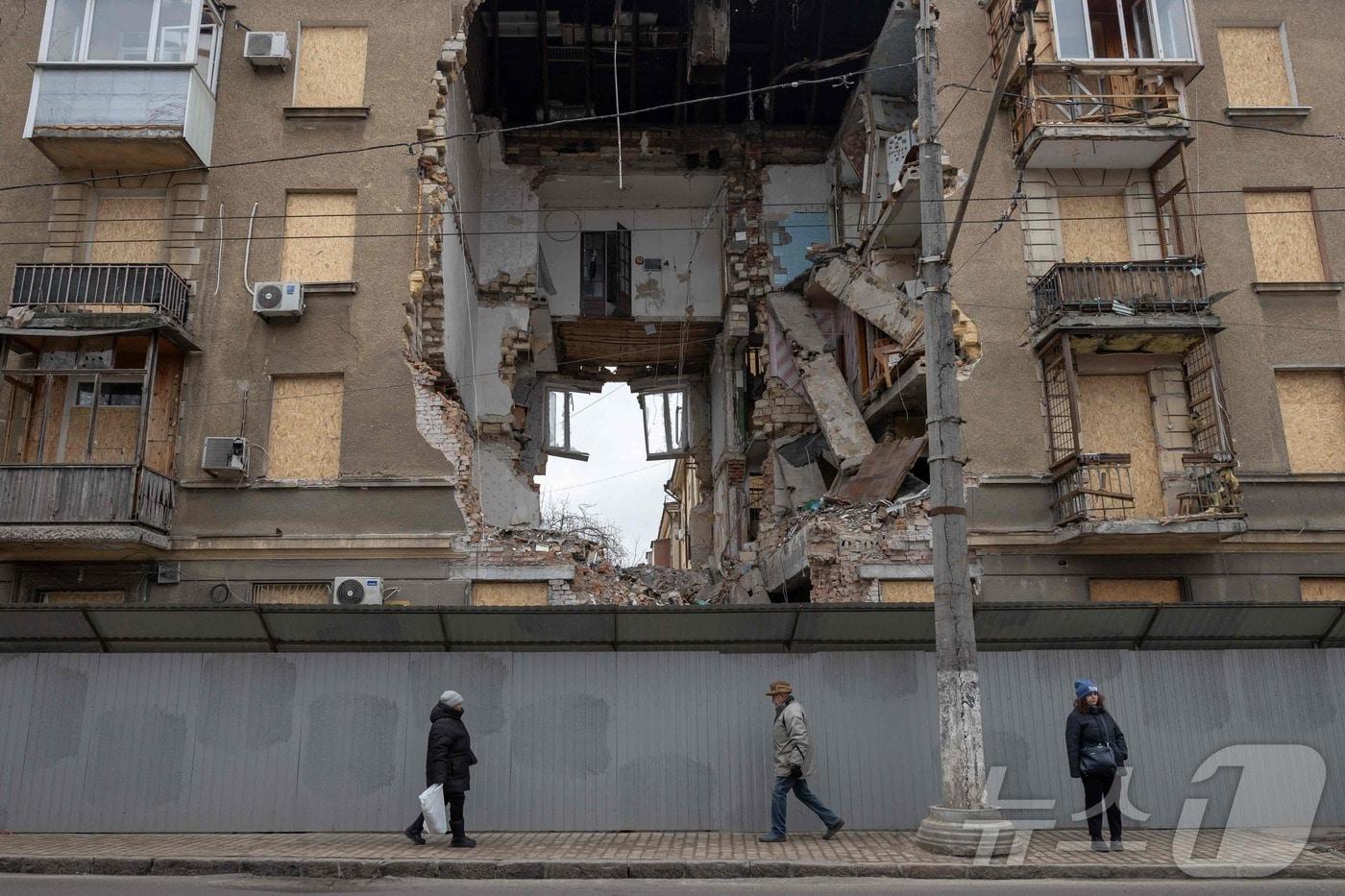 본문 이미지 - 17일(현지시간) 우크라이나 오데사에서 러시아군의 공습으로 크게 파손된 건물 앞을 시민들이 지나고 있다. 2026.02.16. ⓒ AFP=뉴스1
