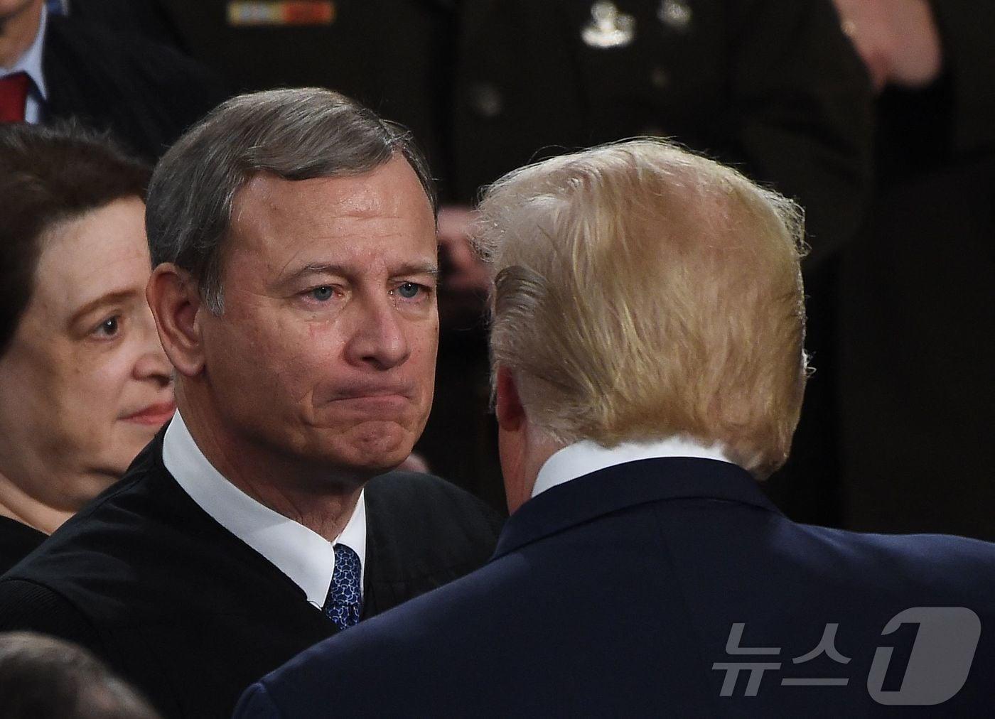 본문 이미지 - 도널드 트럼프 미국 대통령의 첫 임기 때인 2020년 2월 4일(현지시간) 미국 워싱턴DC 국회의사당에 국정연설을 위해 도착한 트럼프 대통령을 존 로버츠 연방대법원장(왼쪽)이 맞이하고 있다. 2026.02.21. ⓒ AFP=뉴스1