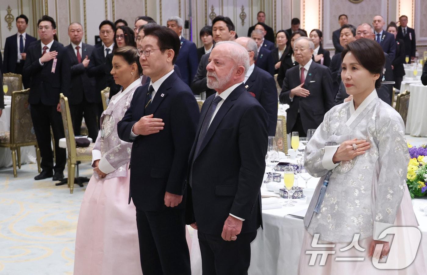 본문 이미지 - 이재명 대통령이 23일 청와대에서 열린 루이스 이나시우 룰라 다시우바 브라질 대통령 국빈 방한 환영 만찬에서 국민의례를 하고 있다. 왼쪽부터 루이스 이나시우 룰라 다시우바 브라질 대통령 부인 호잔젤라 다시우바 여사, 이 대통령, 룰라 대통령, 김혜경 여사. (청와대통신사진기자단) 2026.2.23 ⓒ 뉴스1 이재명 기자