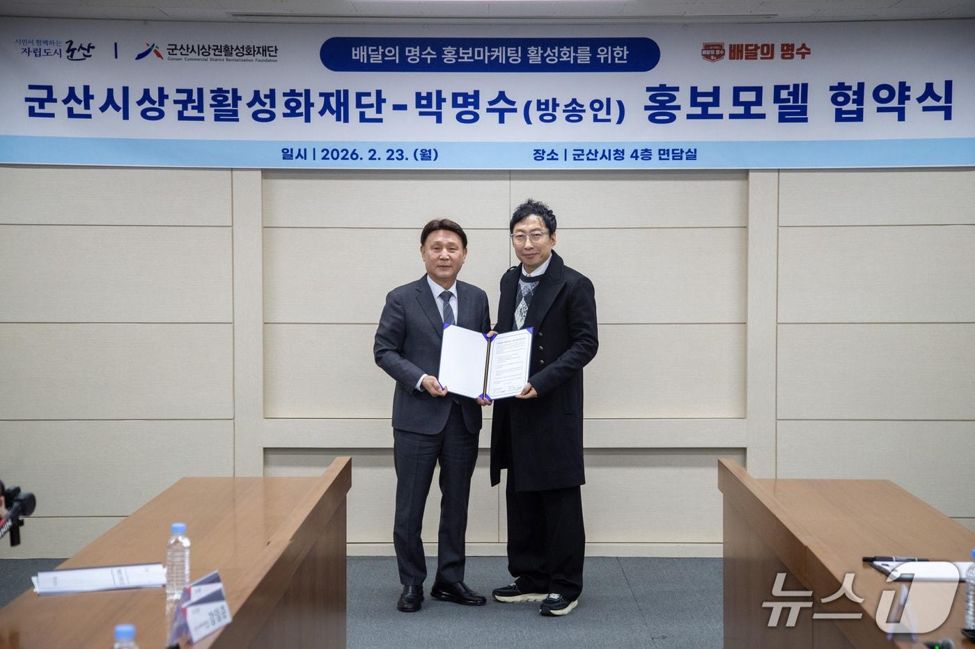 본문 이미지 - 강임준 군산시 상권활성화재단 이사장(사진 왼쪽)과 개그맨 박명수가 공공배달앱 '배달의명수' 홍보마케팅 활성화를 위한 협약식을 체결하고 있다.(군산시 제공, 재판매 및 DB금지)