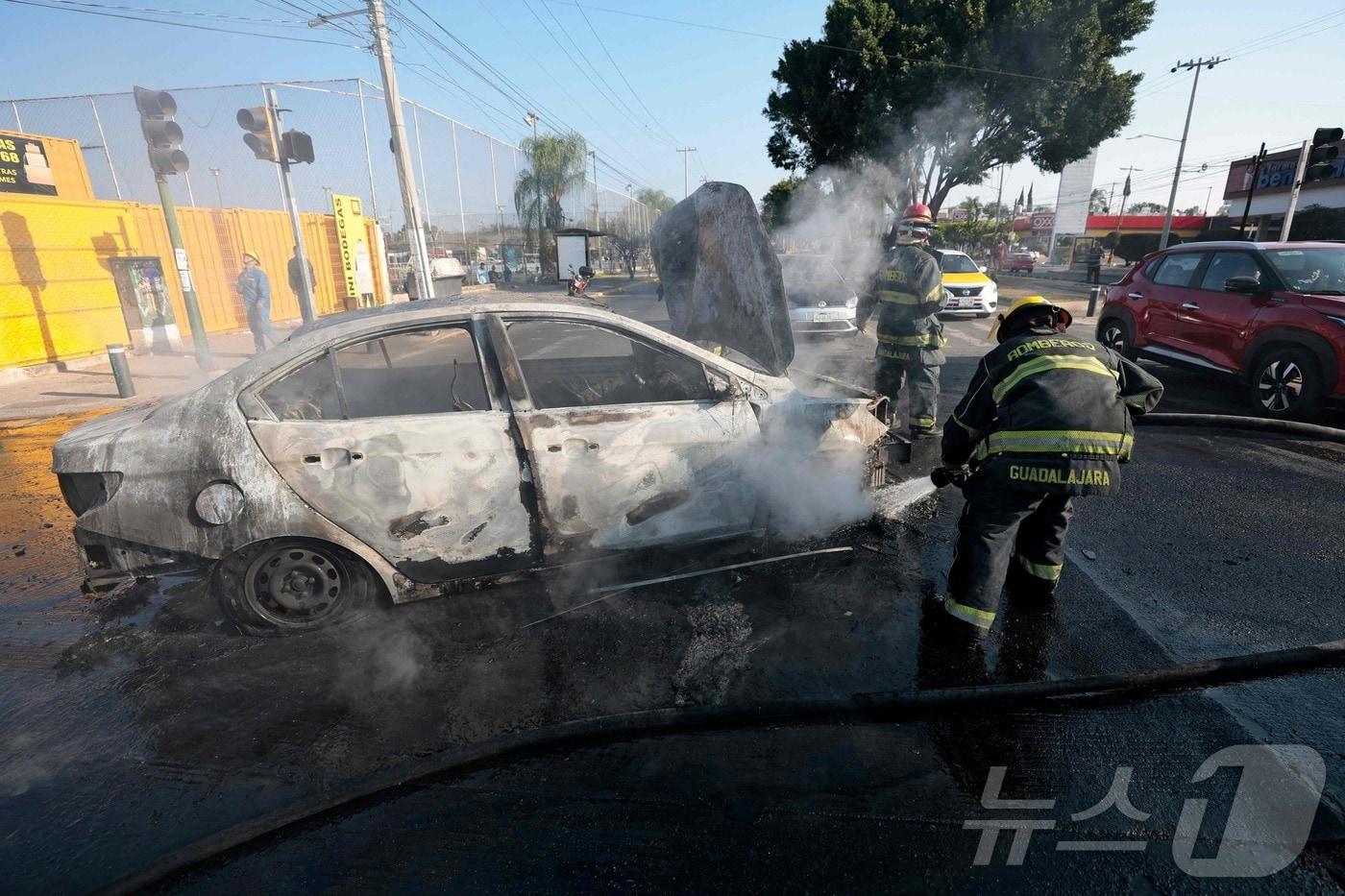 본문 이미지 - 멕시코 할리스코주 과달라하라에서 소방관들이 차량에 붙은 불을 끄고 있다.ⓒ AFP=뉴스1