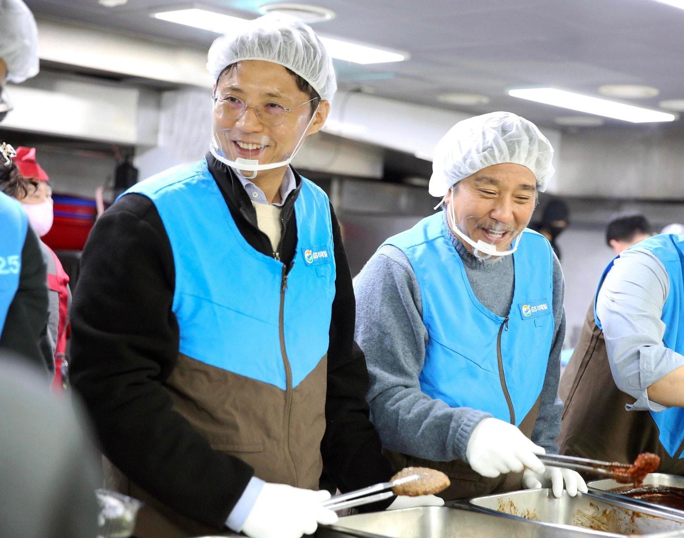 본문 이미지 - 허서홍 GS리테일 대표(왼쪽)와 에드워드 리 셰프(오른쪽)가 사회복지법인 안나의 집에서 급식소 이용자들에게 식사를 제공하고 있다.(GS리테일 제공)