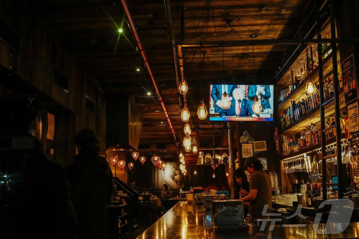 본문 이미지 - 도널드 트럼프 미국 대통령이 24일(현지시간) 워싱턴 DC 미국 국회의사당 하원 회의장에서 2기 첫 국정연설을 하는 모습이 뉴욕 시내의 한 술집 스크린에 비춰지고 있다. 2026.02.24. ⓒ 로이터=뉴스1