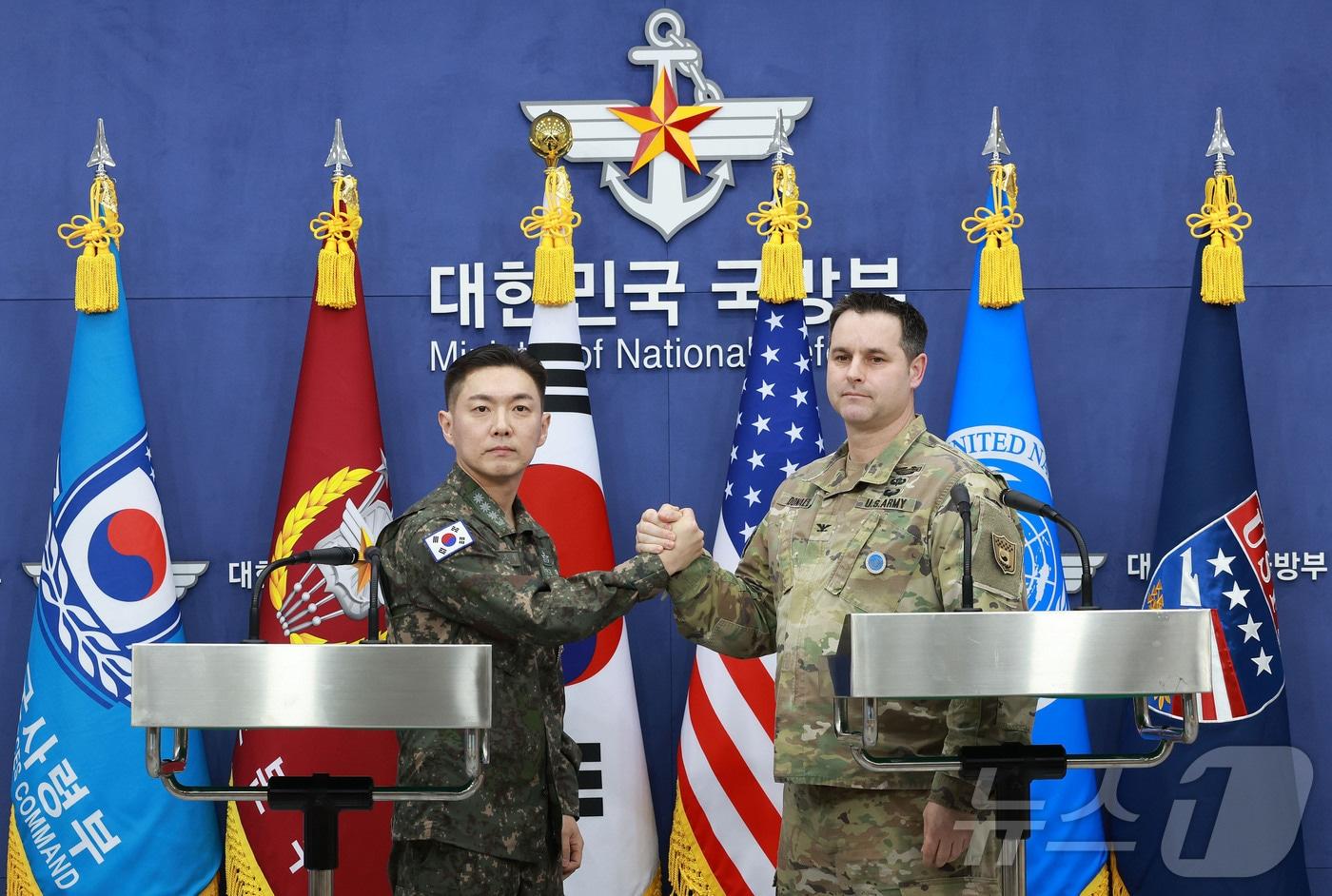 본문 이미지 - 장도영 합동참모본부 공보실장과 라이언 도날드 주한미군사 공보실장이 25일 오후 서울 용산구 국방부에서 2026 자유의 방패(FS) 연습 계획을 발표한 후 손을 맞잡고 있다. 2026.2.25 ⓒ 뉴스1 사진공동취재단