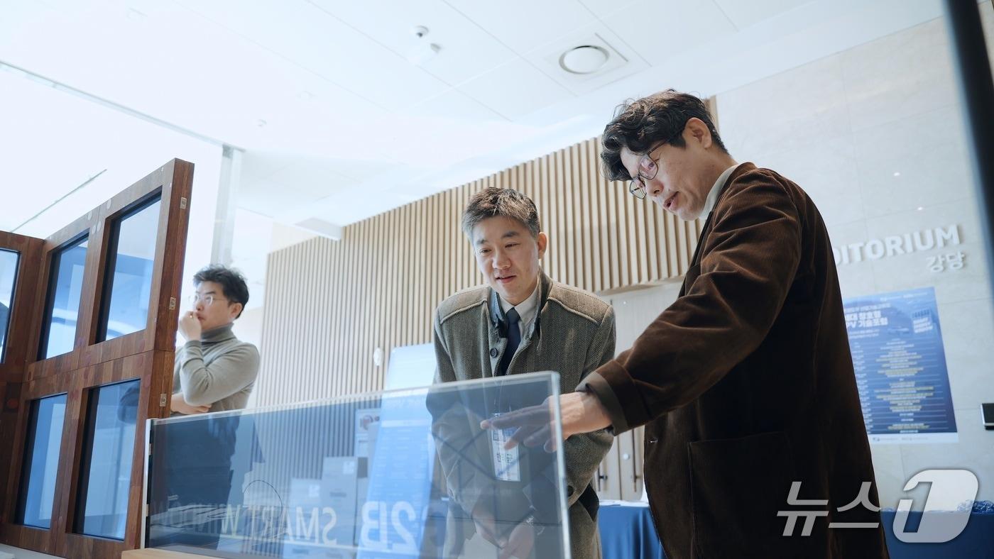 본문 이미지 - 25일 부산 남구 부산국제금융센터(BIFC)에서 열린 차세대 창호형 BIPV 기술포럼에서 참가자가 지능형 조절 특성을 가진 스마트 유리 제품 시연을 보고 있다. ⓒ 뉴스1