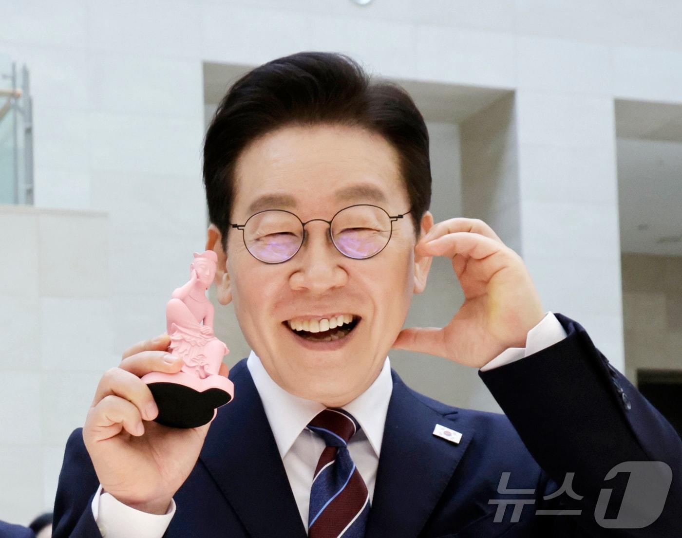 본문 이미지 - 이재명 대통령이 26일 서울 용산구 국립중앙박물관에서 열린 특별전 '우리들의 이순신'을 관람한 뒤 기념품을 들고 기념촬영을 하고 있다. 2026.2.26 ⓒ 뉴스1 허경 기자