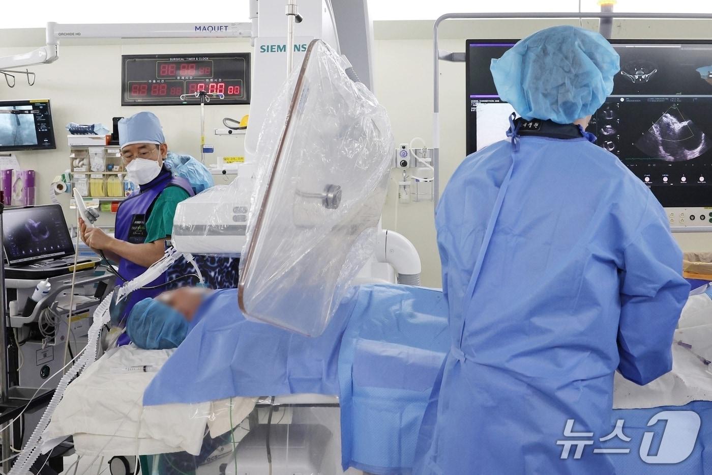 본문 이미지 - 송종민 서울아산병원 심장내과 교수(왼쪽)가 심방중격결손 경피적 폐쇄술 중 심장초음파로 결손 부위를 정밀하게 확인하며 함께 시술을 시행하고 있다. 이때 시술 전 3차원 경식도 심초음파를 시행해 심방 결손의 크기와 모양을 정밀하게 측정해 시술 성공률과 안전성을 크게 높였다.(서울아산병원 제공)