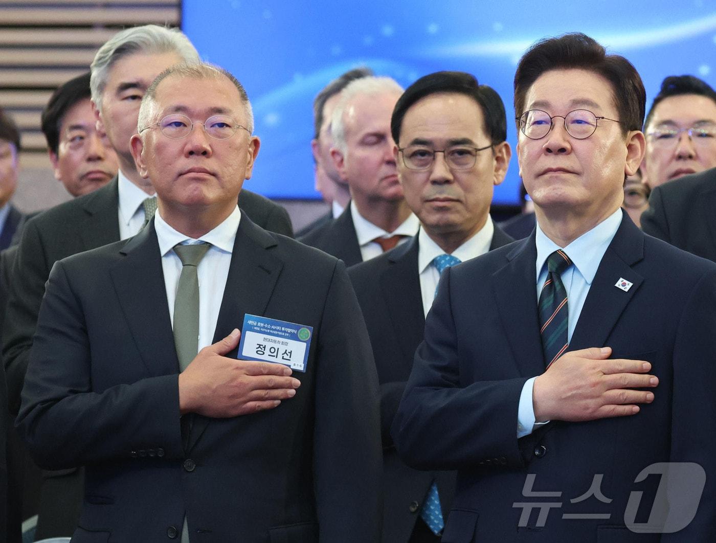 본문 이미지 - 이재명 대통령과 정의선 현대자동차 회장이 27일 전북 군산시 새만금 컨벤션센터에서 열린 새만금 로봇·수소·AI 시티 투자협약식에서 국민의례를 하고 있다. 2026.2.27 ⓒ 뉴스1 이재명 기자