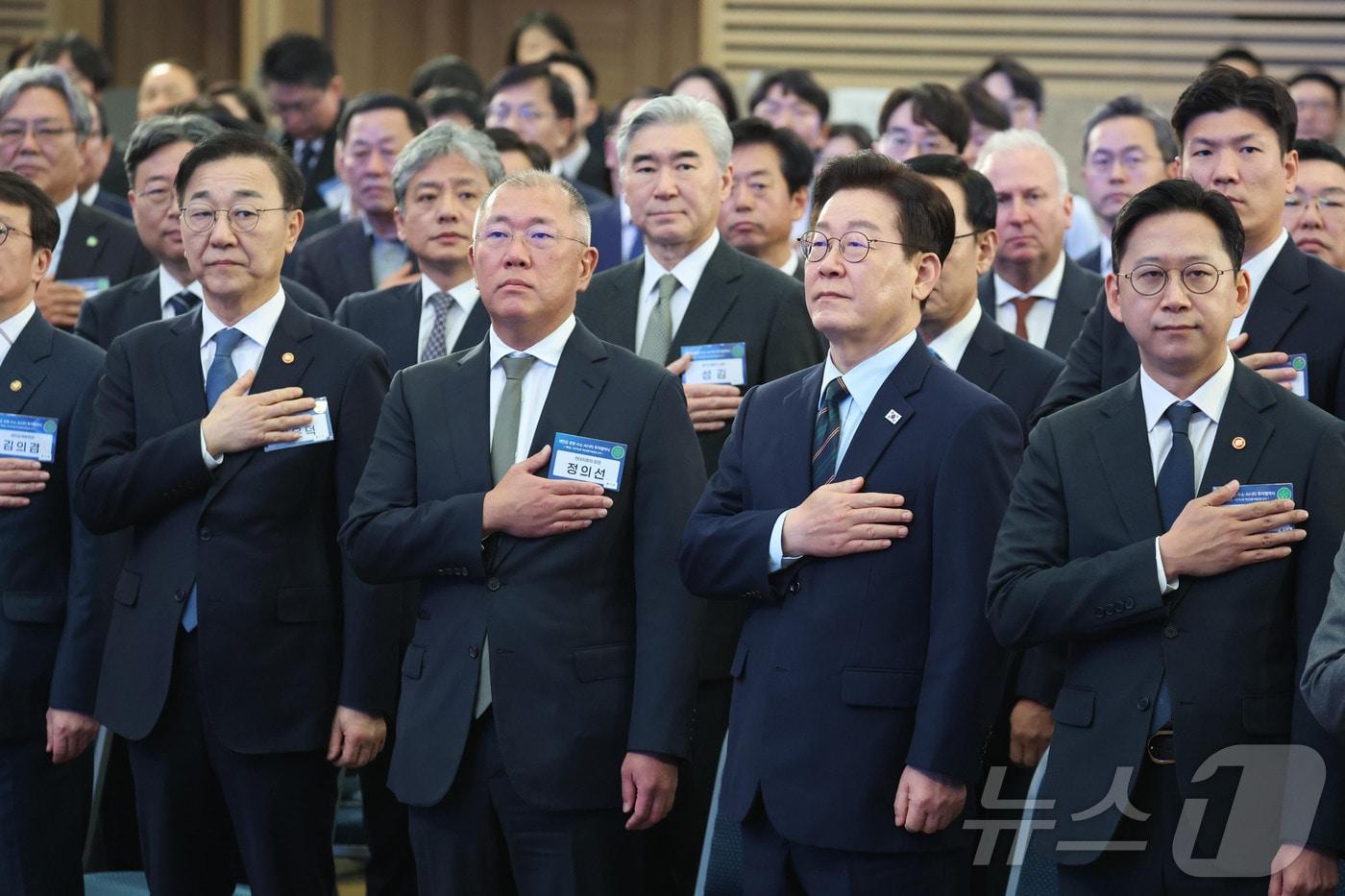 본문 이미지 - 이재명 대통령이 27일 전북 군산시 새만금 컨벤션센터에서 열린 새만금 로봇·수소·AI 시티 투자협약식에서 국민의례를 하고 있다. 왼쪽부터 김윤덕 국토교통부 장관, 정의선 현대자동차 회장, 배경훈 부총리 겸 과학기술정보통신부 장관. 2026.2.27 ⓒ 뉴스1 이재명 기자