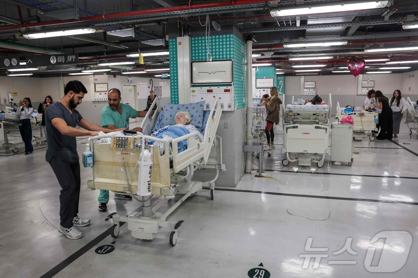 본문 이미지 - 28일(현지시간) 이스라엘 텔아비브의 한 병원 주차장에서 직원들이 환자들을 치료하고 있다. 이날 이스라엘 군 당국은 미국과 함께 이란을 전격 공격하면서 이스라엘 전역에서 공습경보 사이렌을 울렸다. 2026.02.28 ⓒ AFP=뉴스1